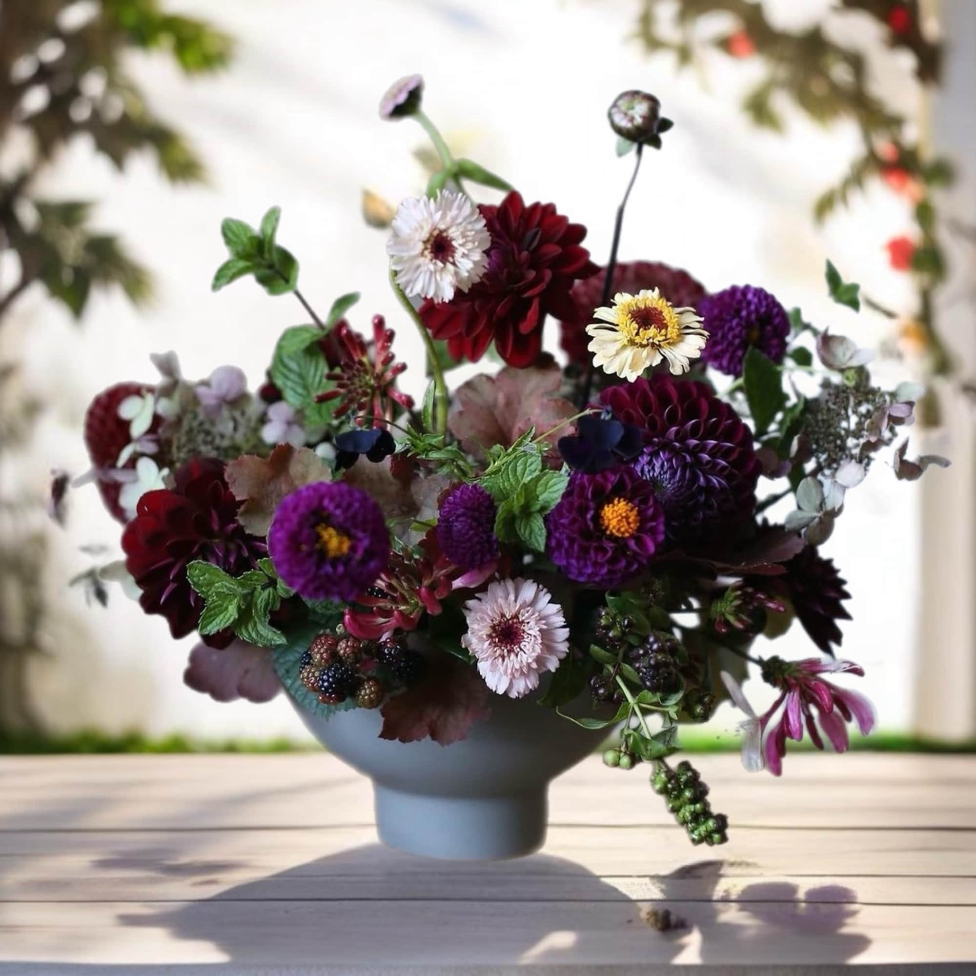 Mixed bouquet of purple, burgundy, and white flowers in a blue vase