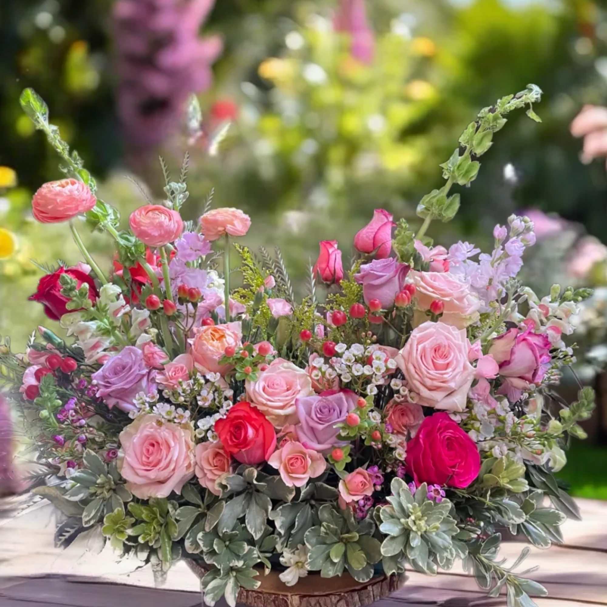 Low floral centerpiece with pink and lavender roses in a shallow container