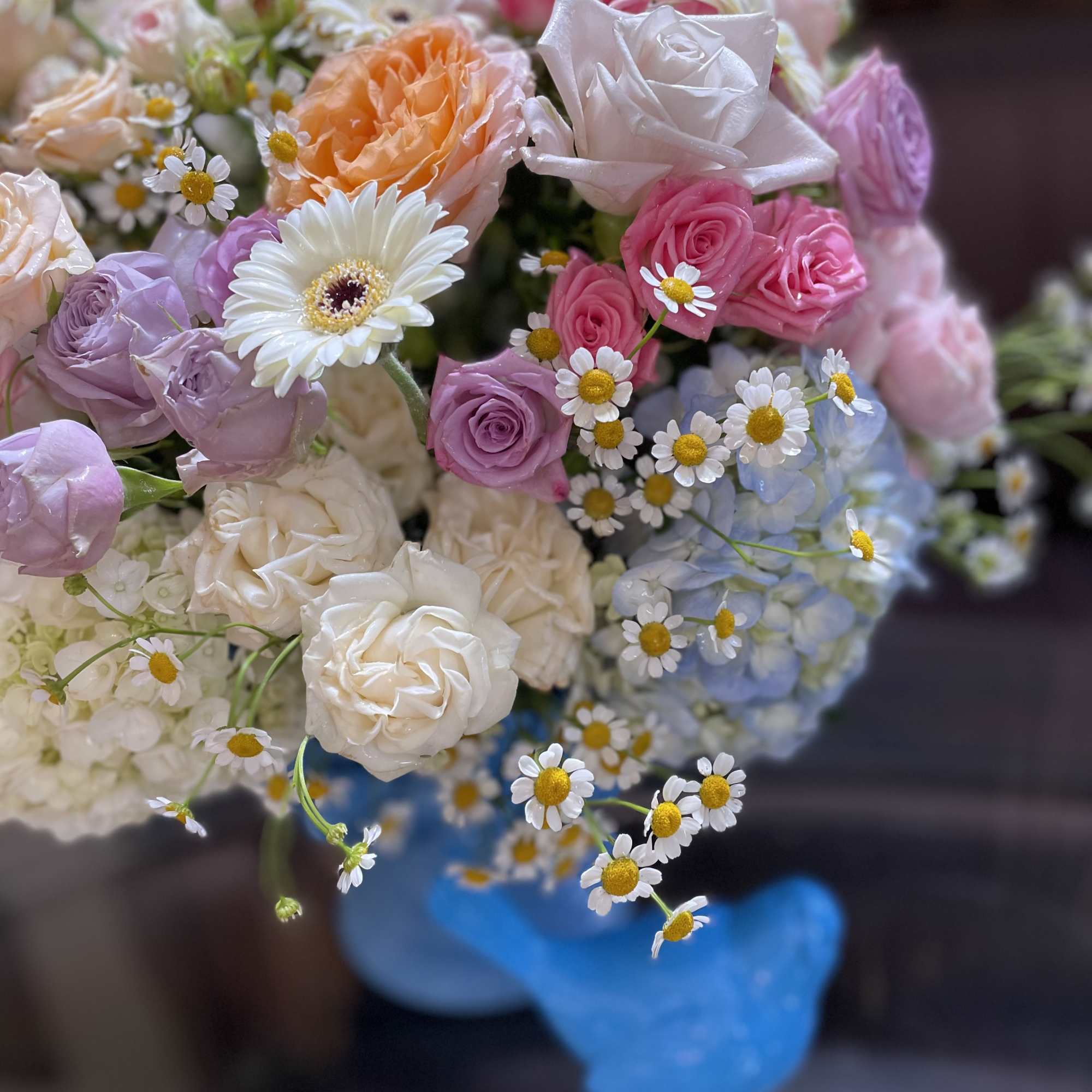 Bouquet of pastel roses, daisies, and hydrangeas in a blue vase