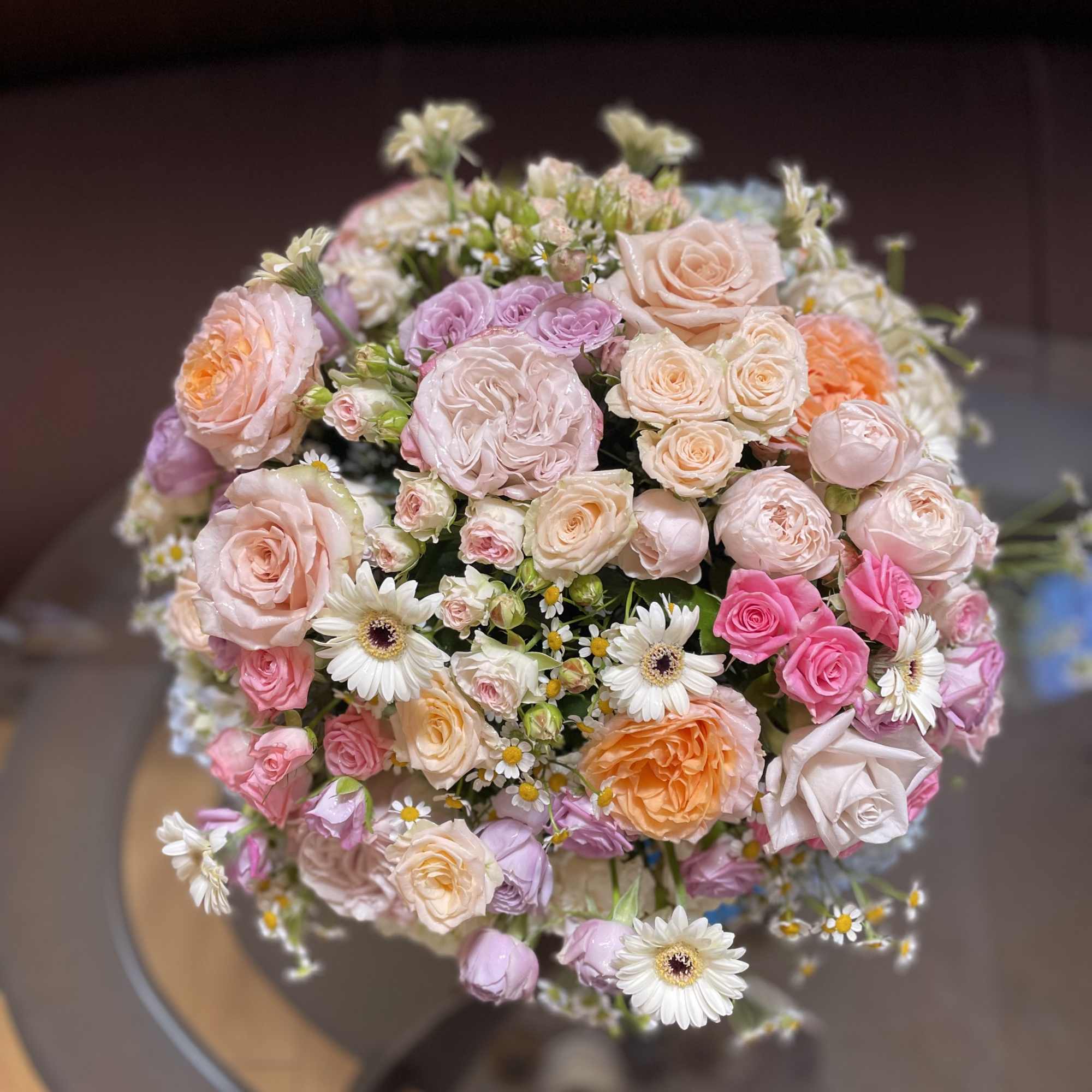Round bouquet of pastel roses and white daisies