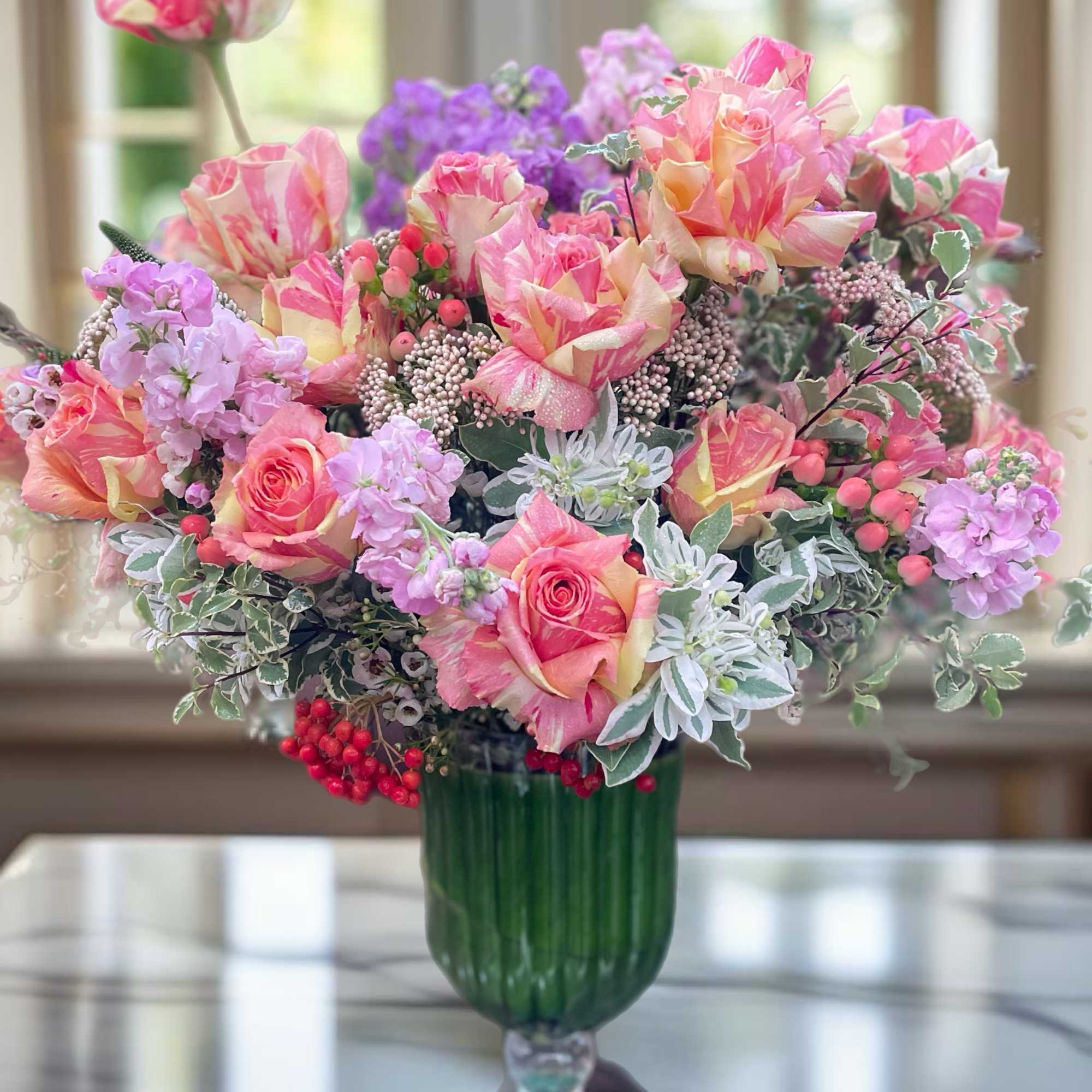 Pink and peach roses arranged in a green glass vase