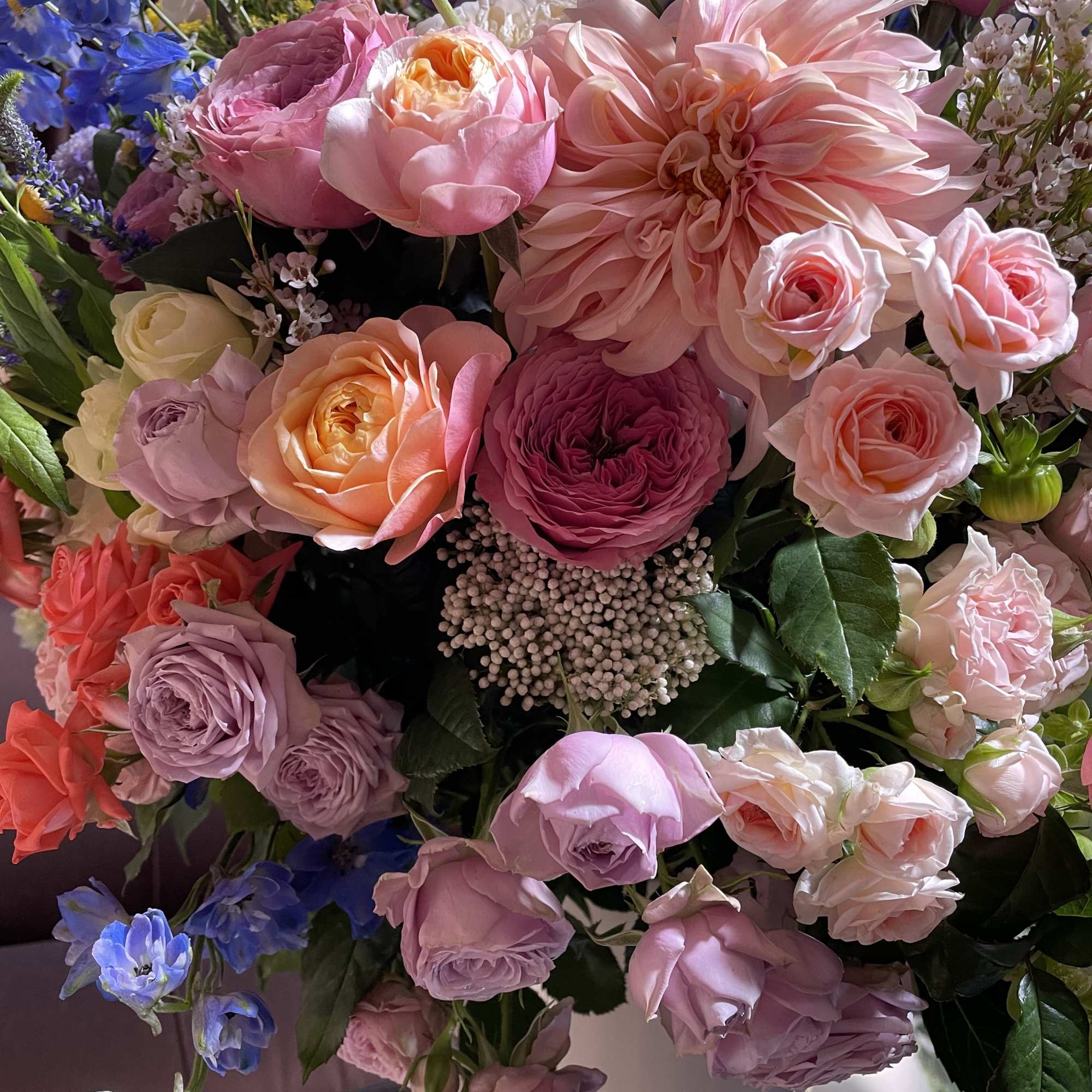 Mixed bouquet of pink, lavender, and blue flowers in a vase