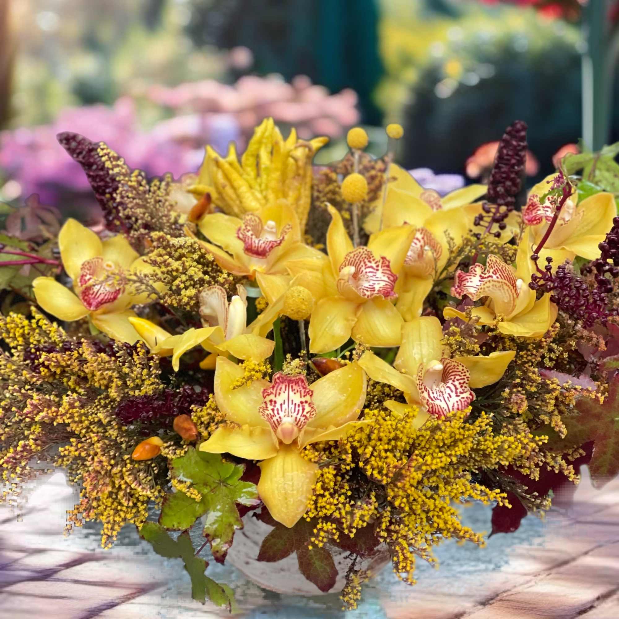 Yellow orchids arranged in a low white pedestal container
