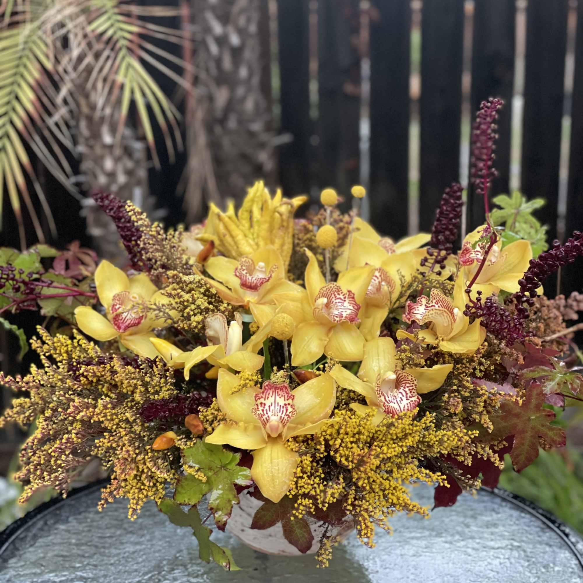 Yellow orchids arranged in a low centerpiece with burgundy accents