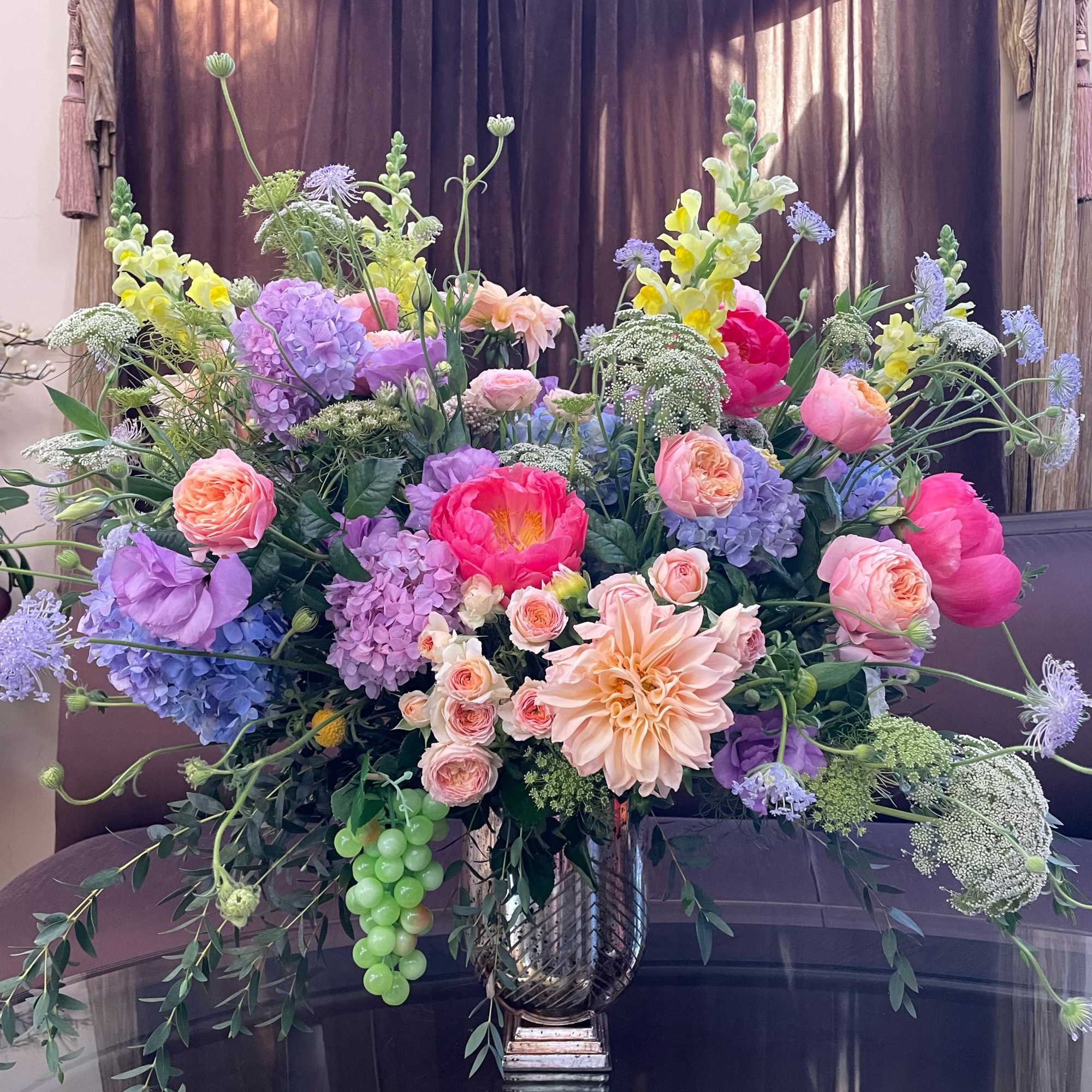 Large mixed bouquet in a metallic vase with pink, purple, and yellow blooms