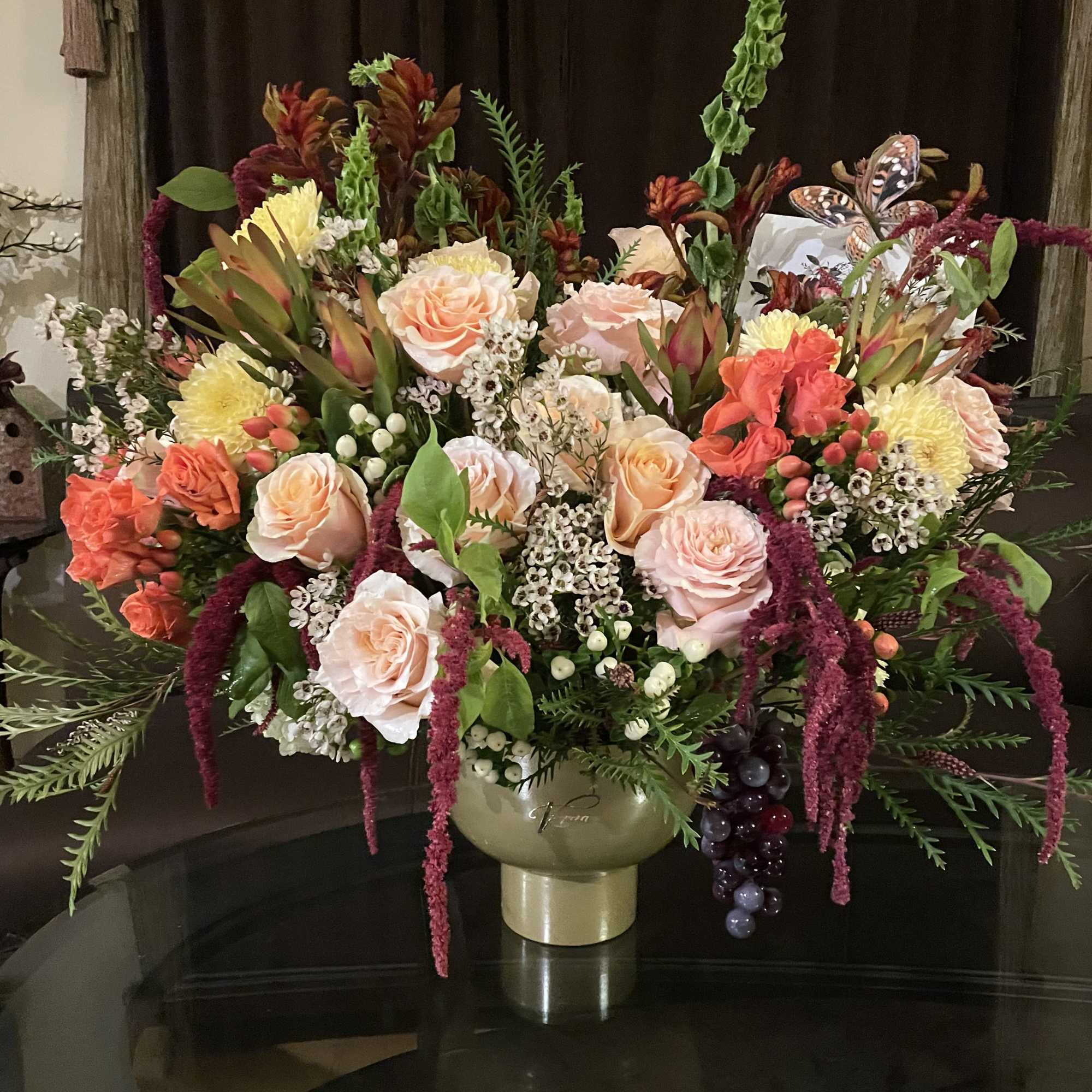 Large mixed floral arrangement in a gold vase with pink and orange roses