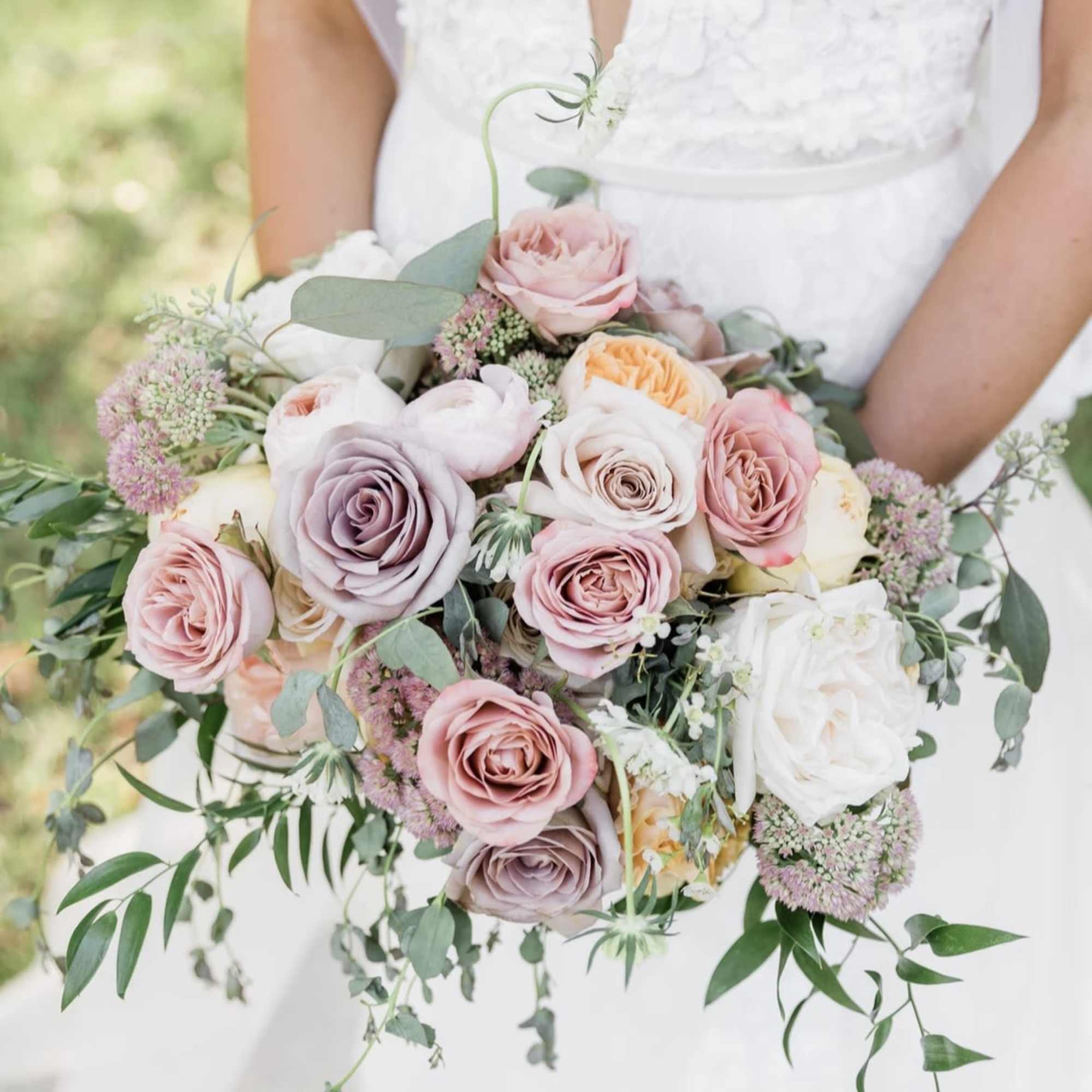 Bridal bouquet of pastel roses with trailing greenery