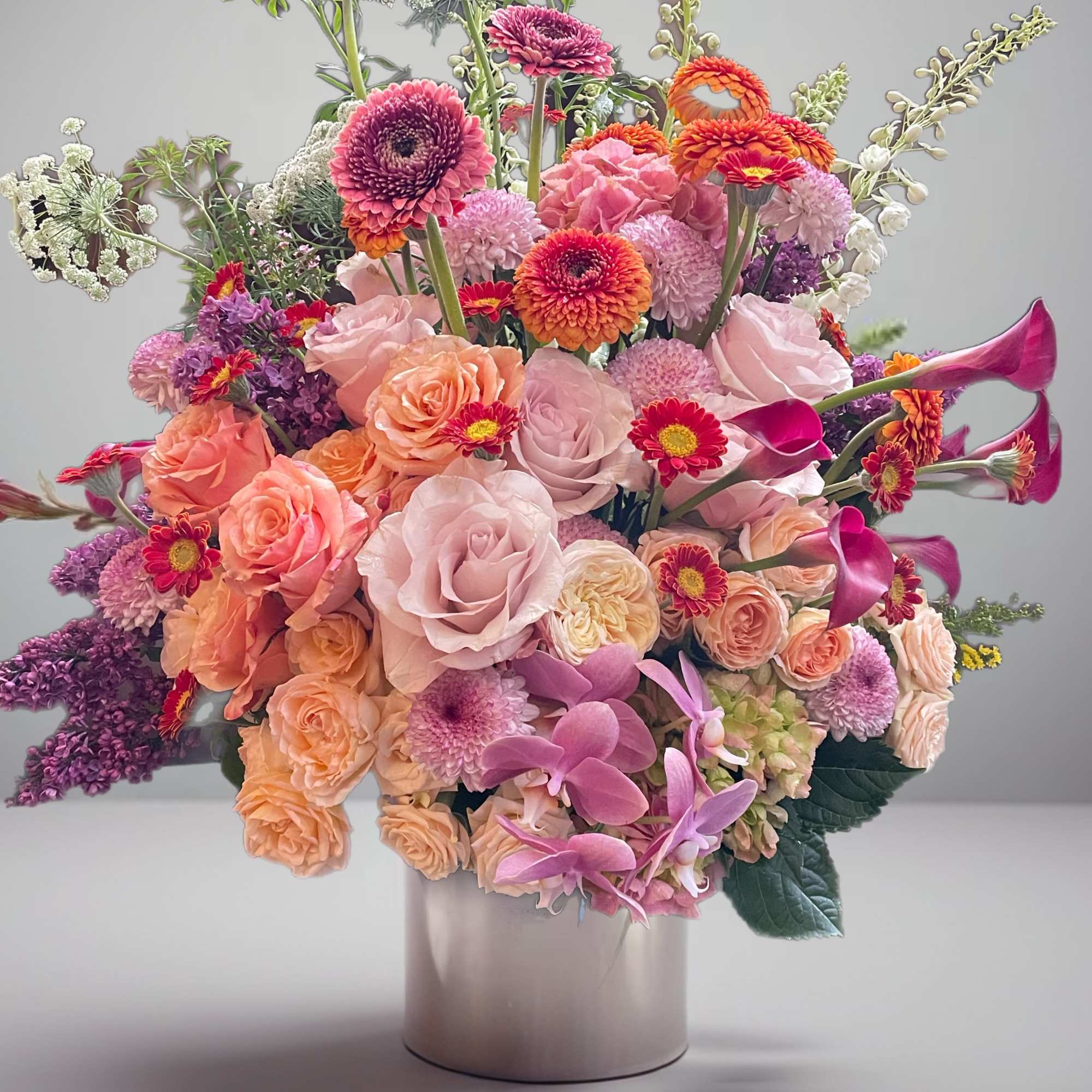 Large mixed bouquet of pink, peach, purple, and white flowers in a vase