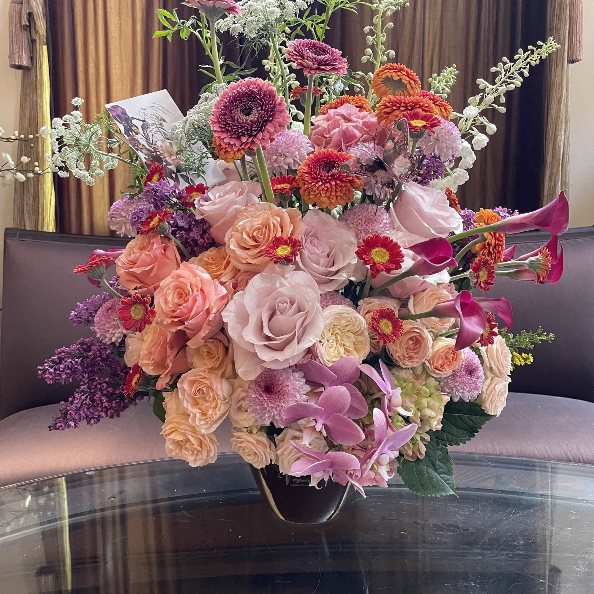 Large mixed bouquet of pink, peach, and purple flowers in a black vase
