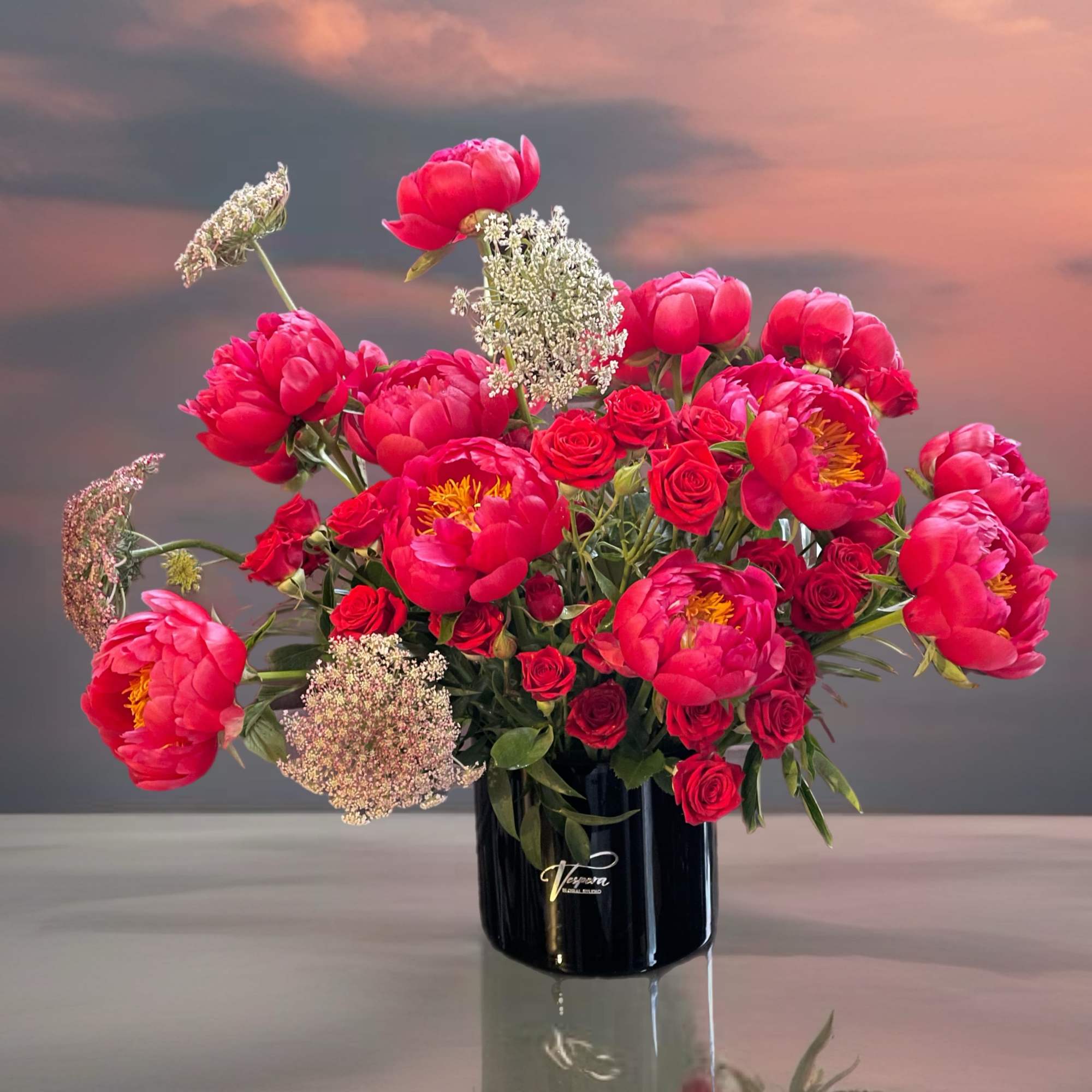 Pink peonies and red roses arranged in a black vase, photo 2 of 3