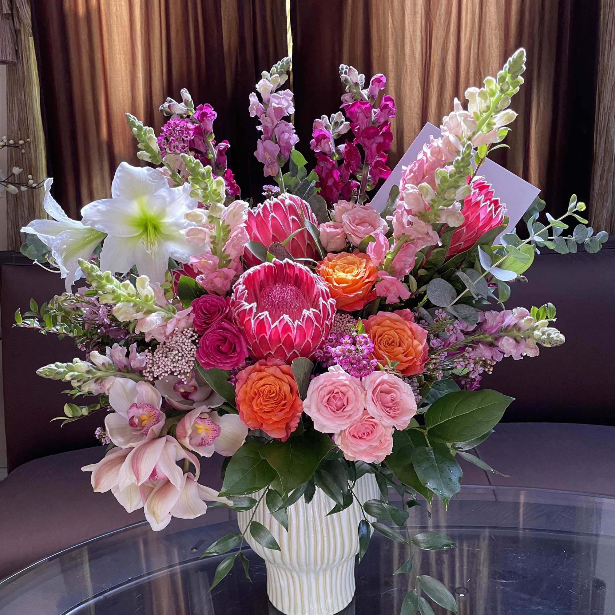Large mixed bouquet in a white vase with pink and orange blooms