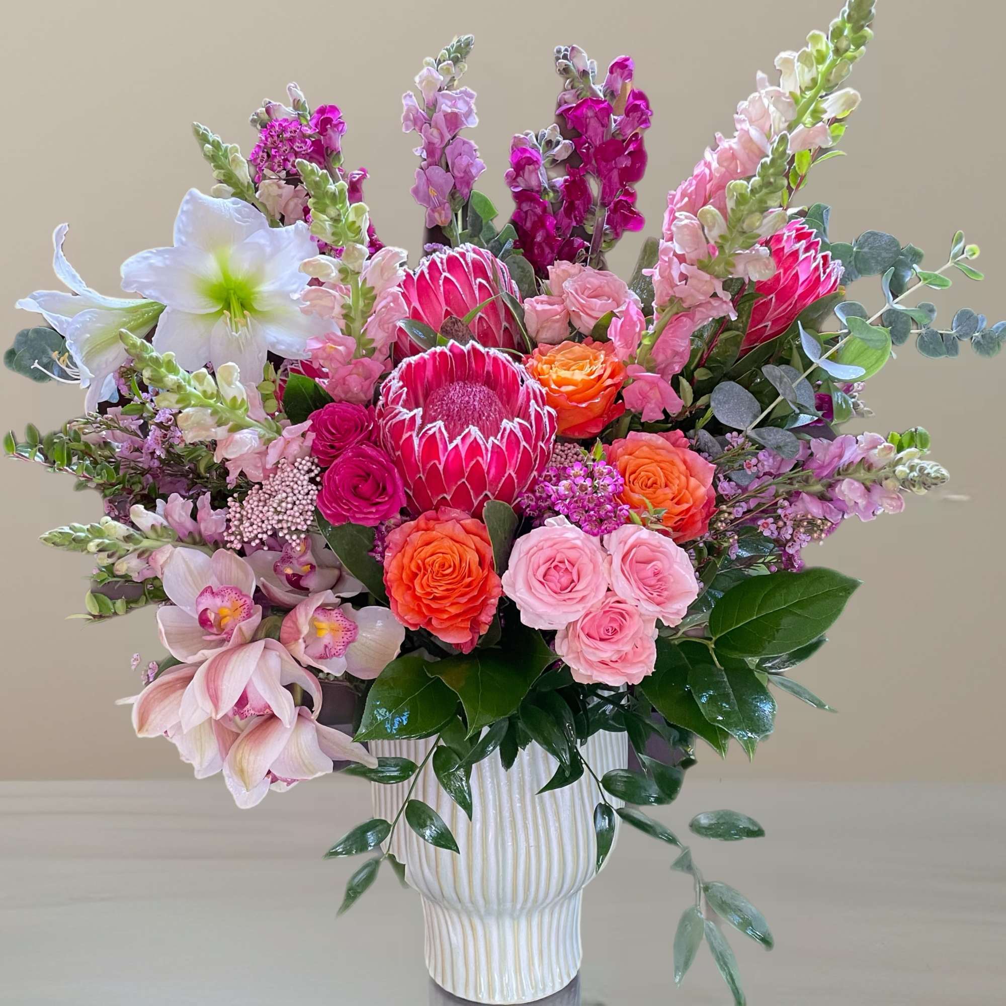 Pink and orange mixed flower arrangement in a white vase