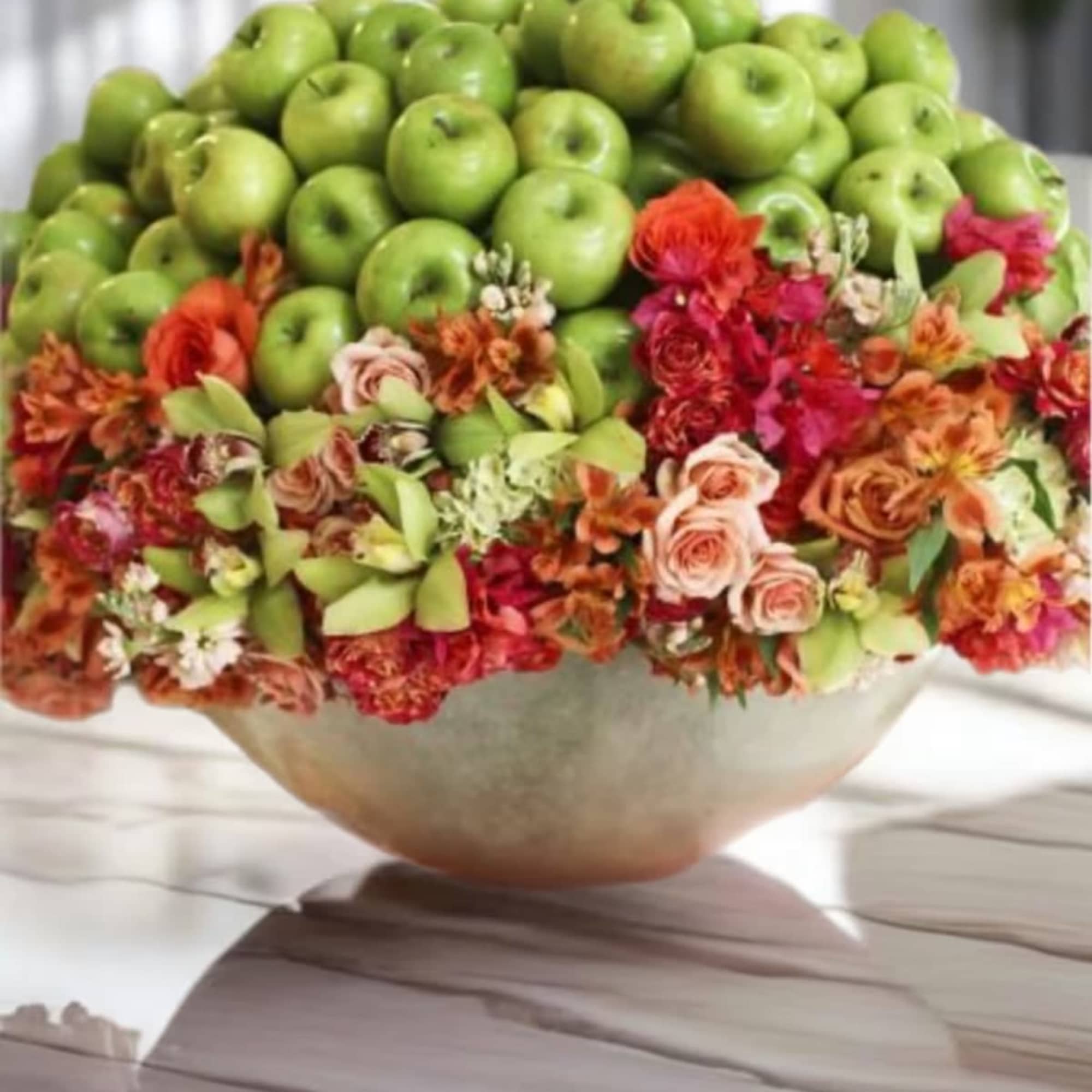 Bowl arrangement of green apples with mixed flowers