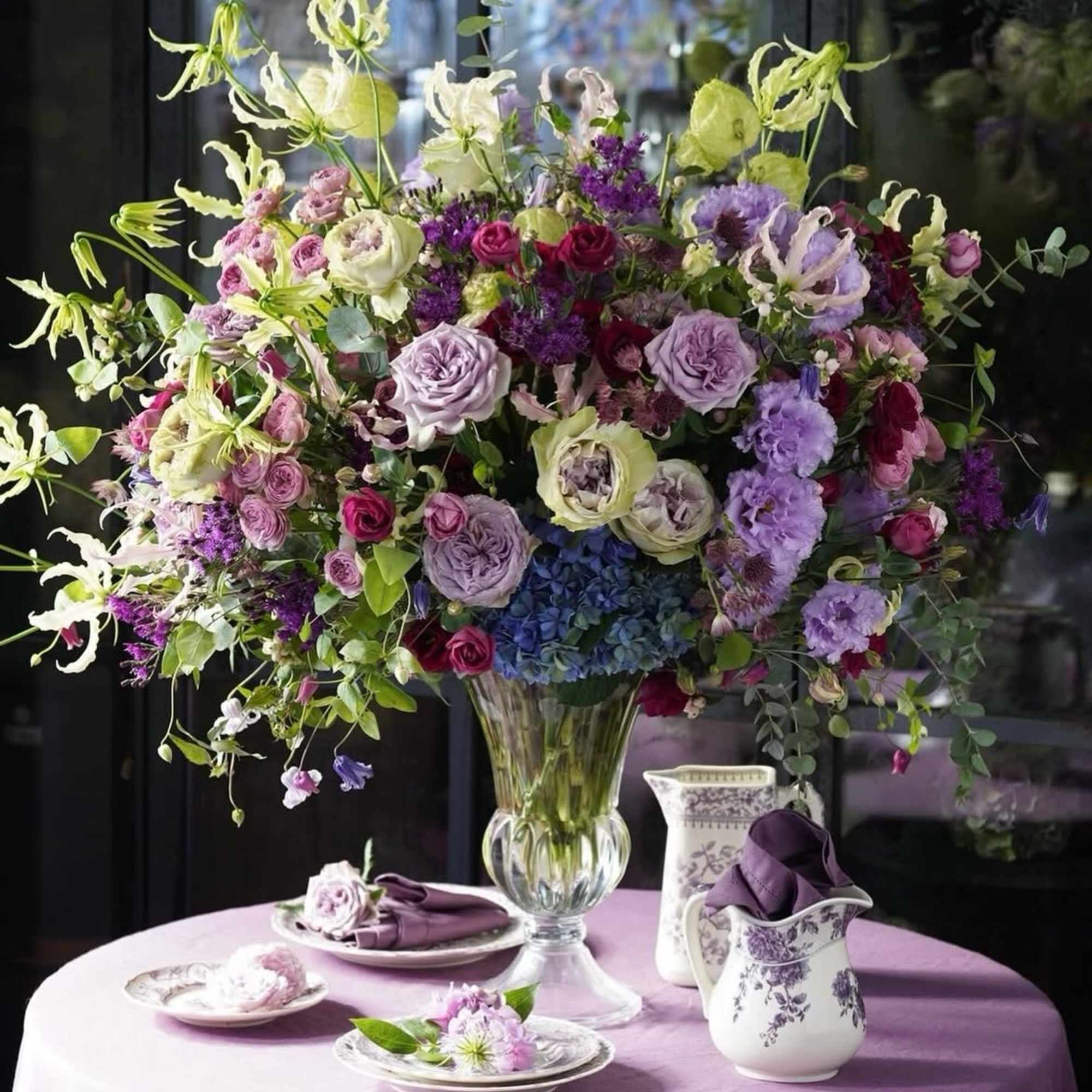 Large lavender and purple floral arrangement in a clear glass vase