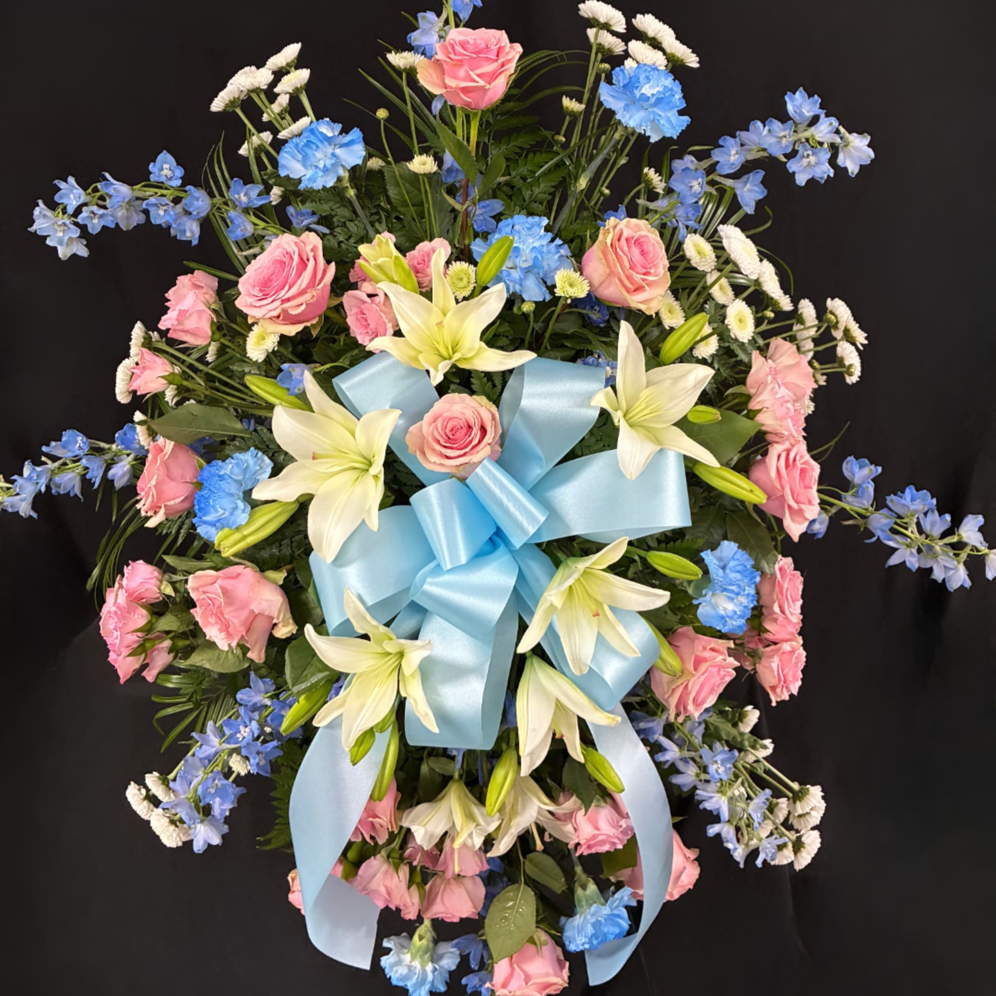 Pink roses and white lilies with blue flowers, tied with a light blue ribbon