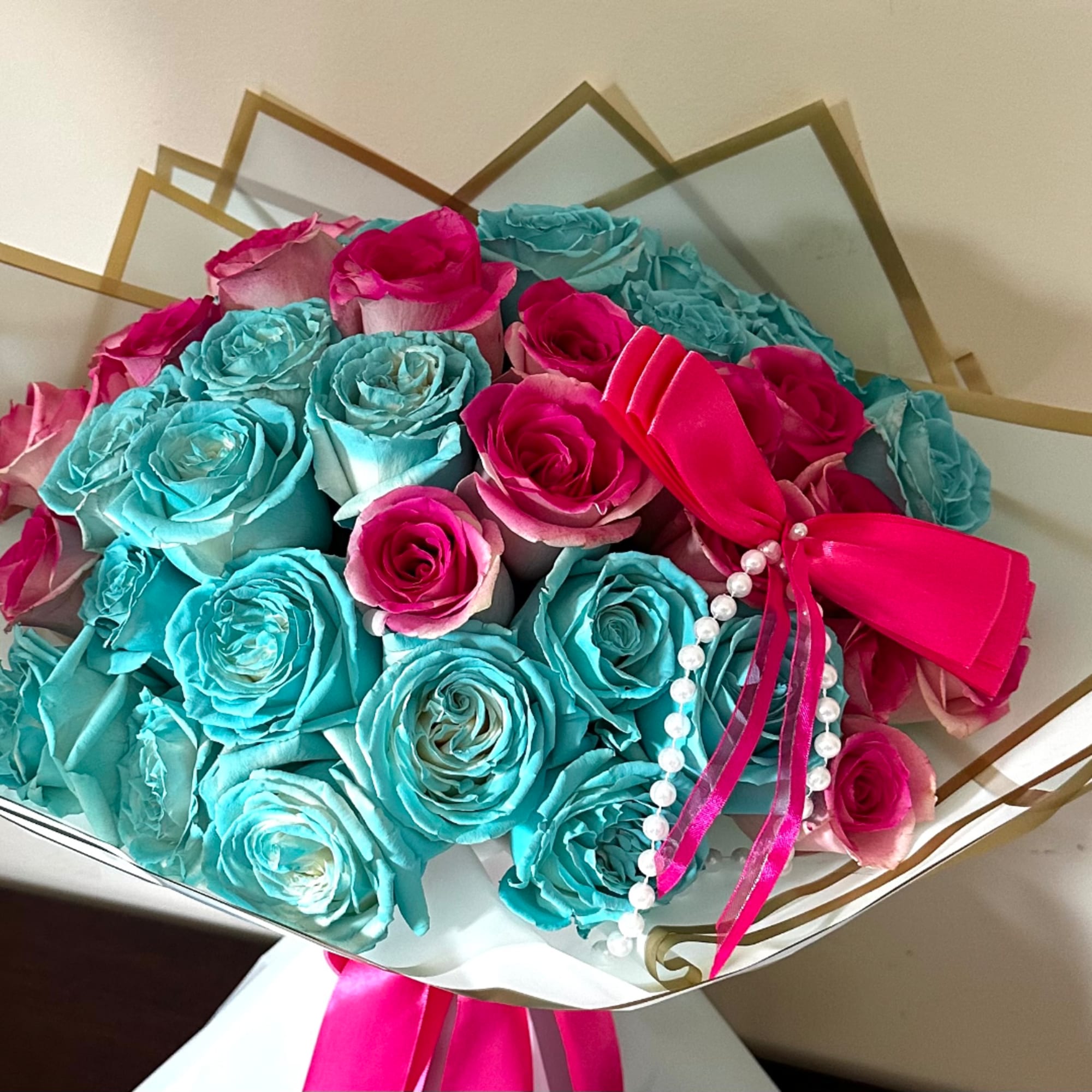 Bouquet of turquoise and pink roses with a bright ribbon and pearl strand