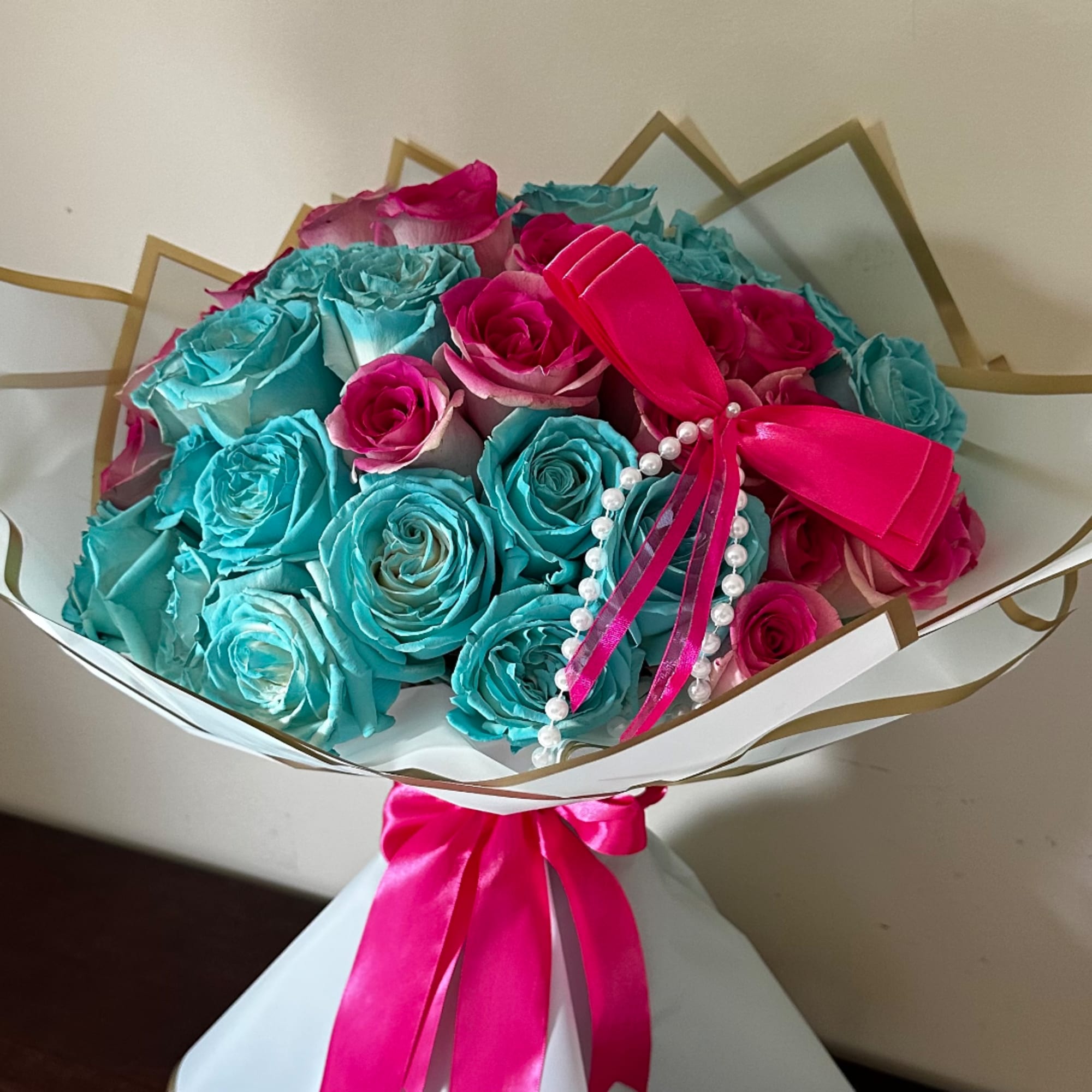Bouquet of turquoise and hot pink roses wrapped with a satin ribbon
