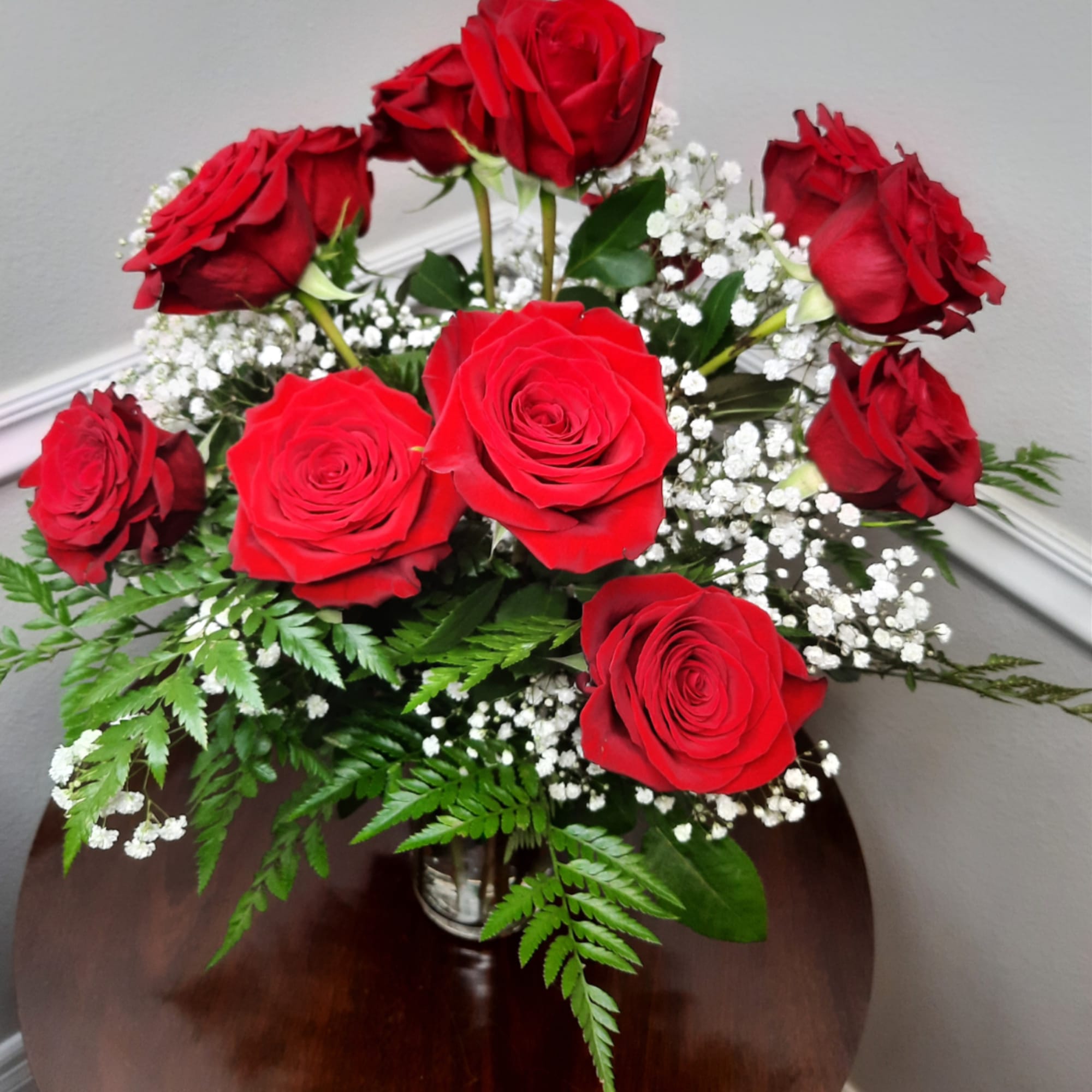 Red roses arranged in a clear vase with baby's breath