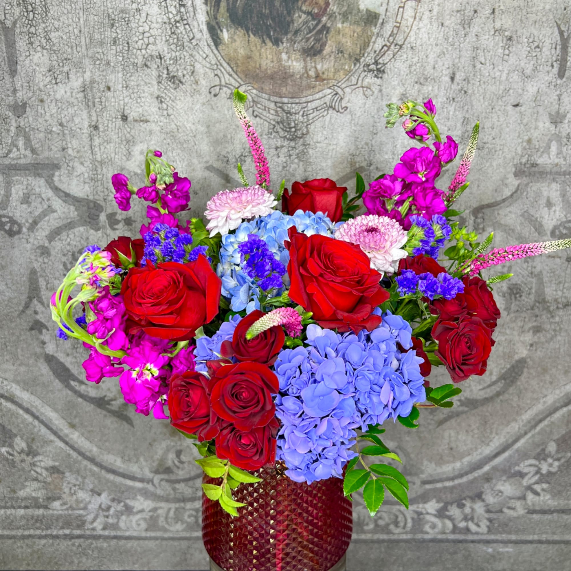 Red roses and blue hydrangeas in a red textured vase