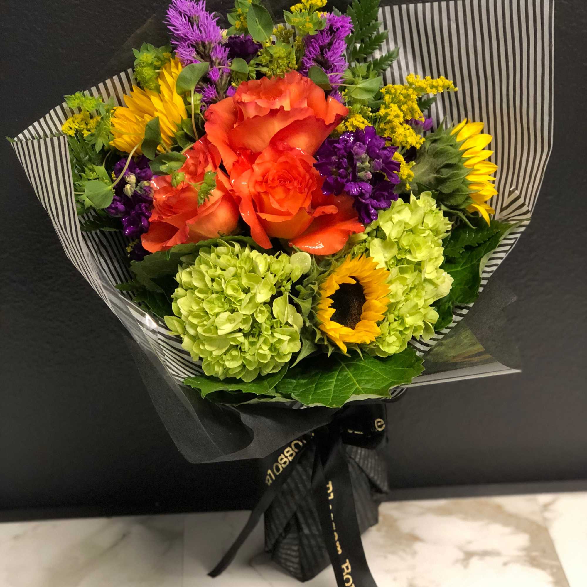 Bright mixed bouquet with orange roses, sunflowers, and green hydrangeas