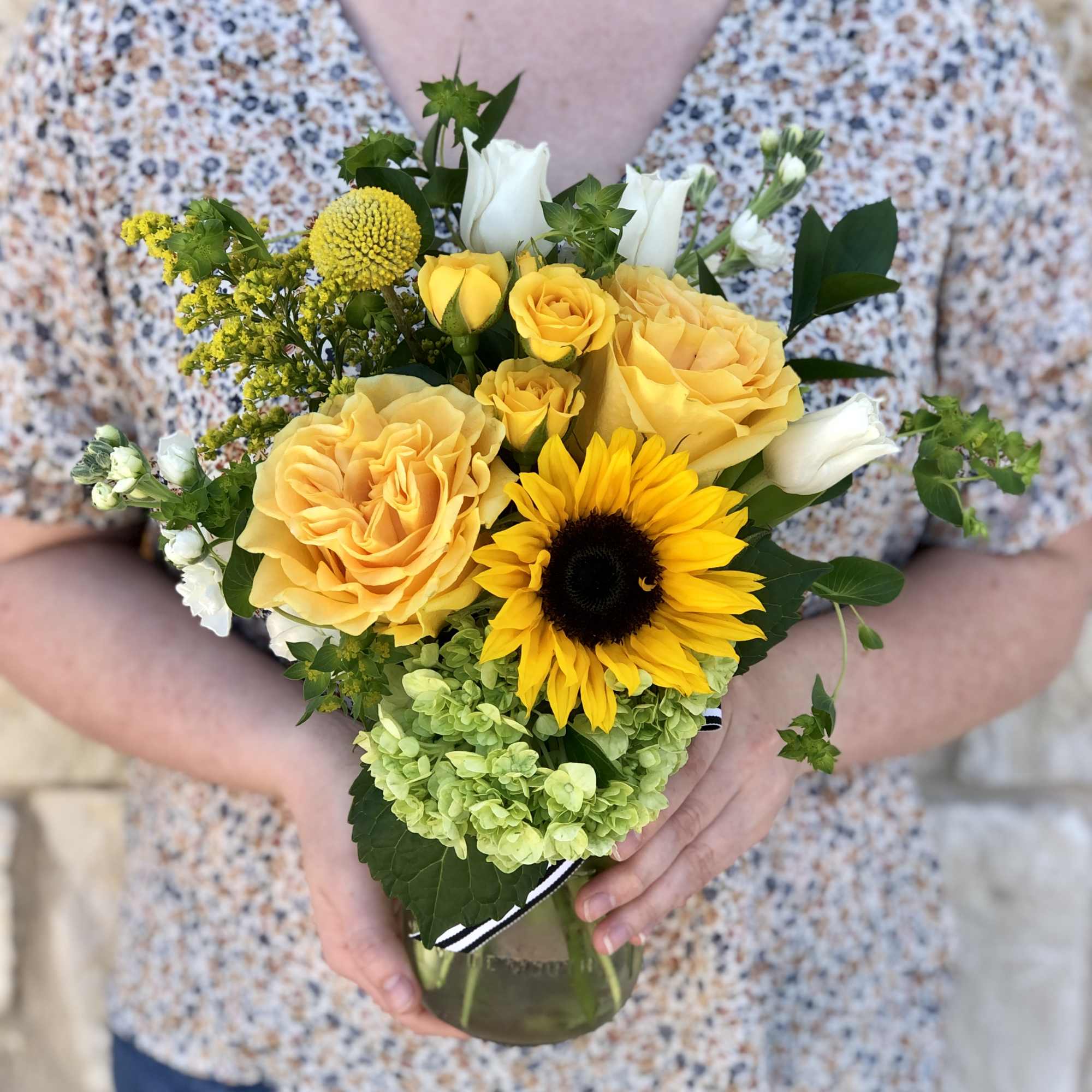 Yellow roses and a sunflower in a glass vase