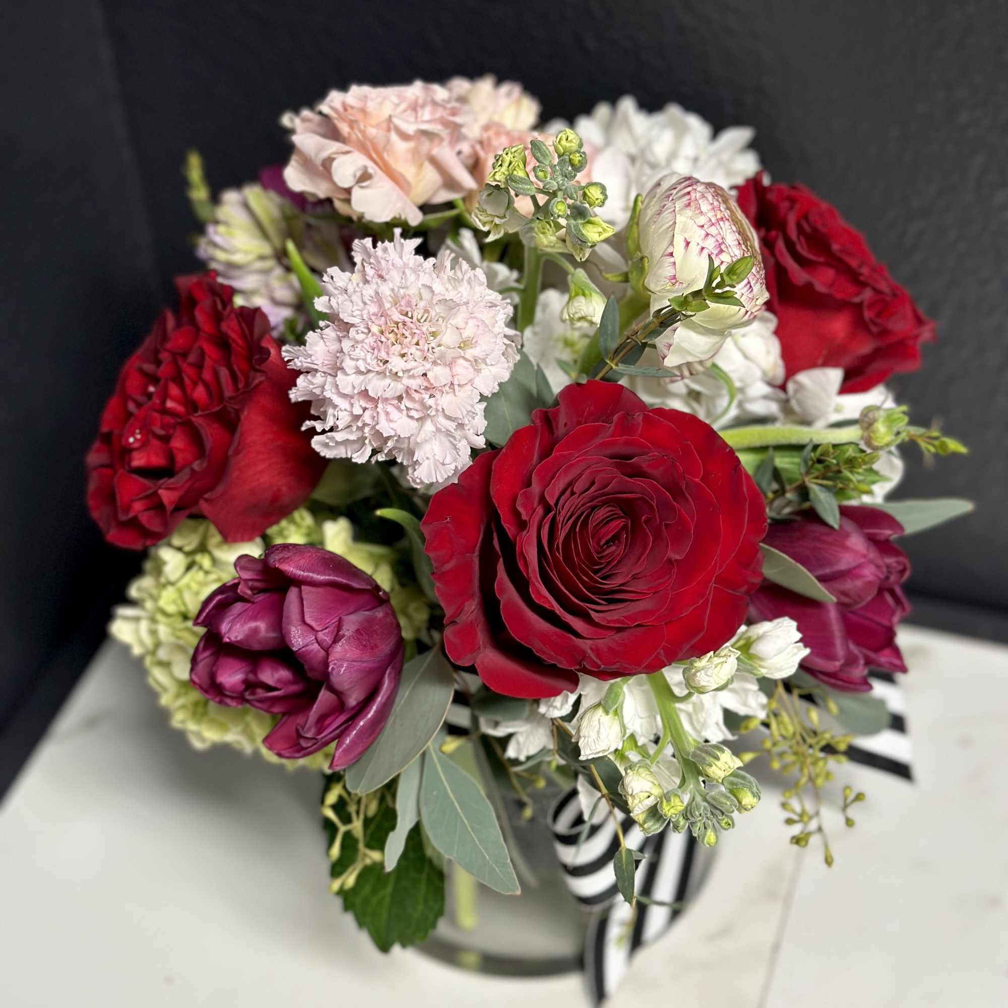 Bouquet of red, pink, and white flowers in a striped container