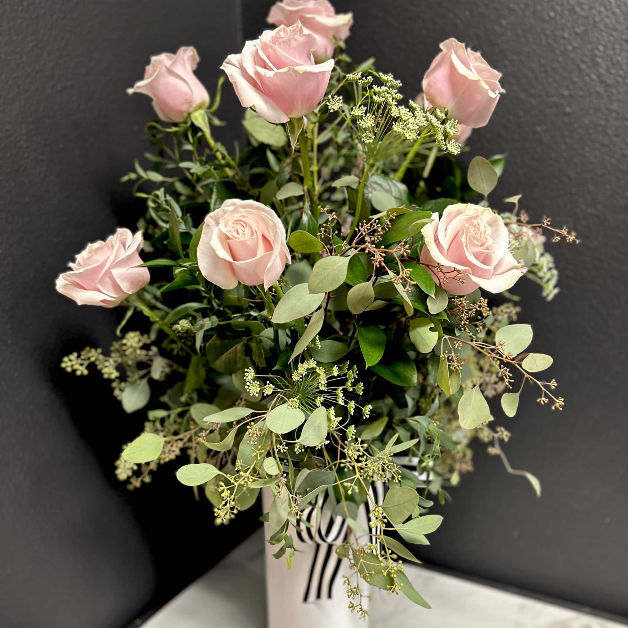 Pink roses in a white vase with airy greenery