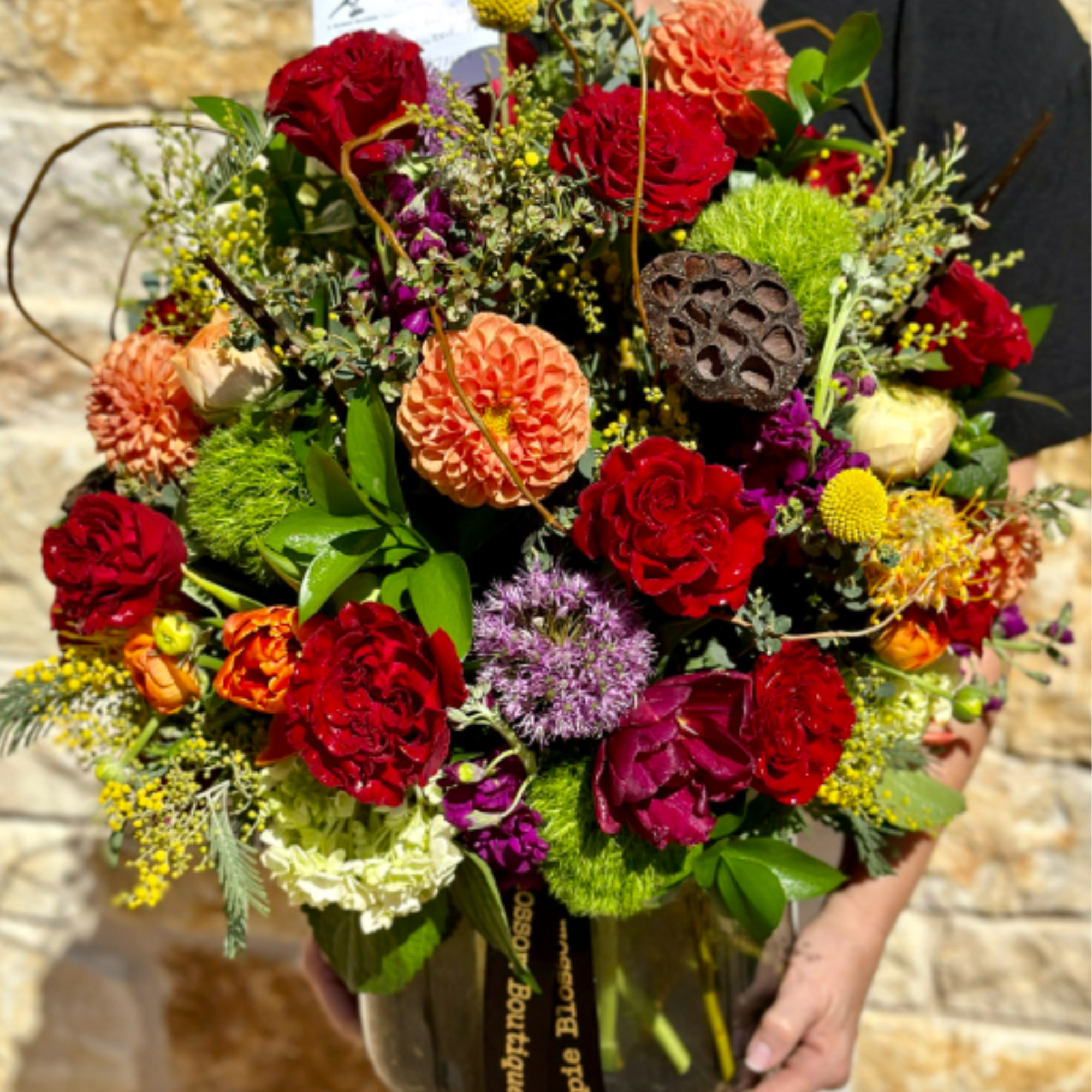 Mixed bouquet of red, orange, and purple flowers in a glass vase