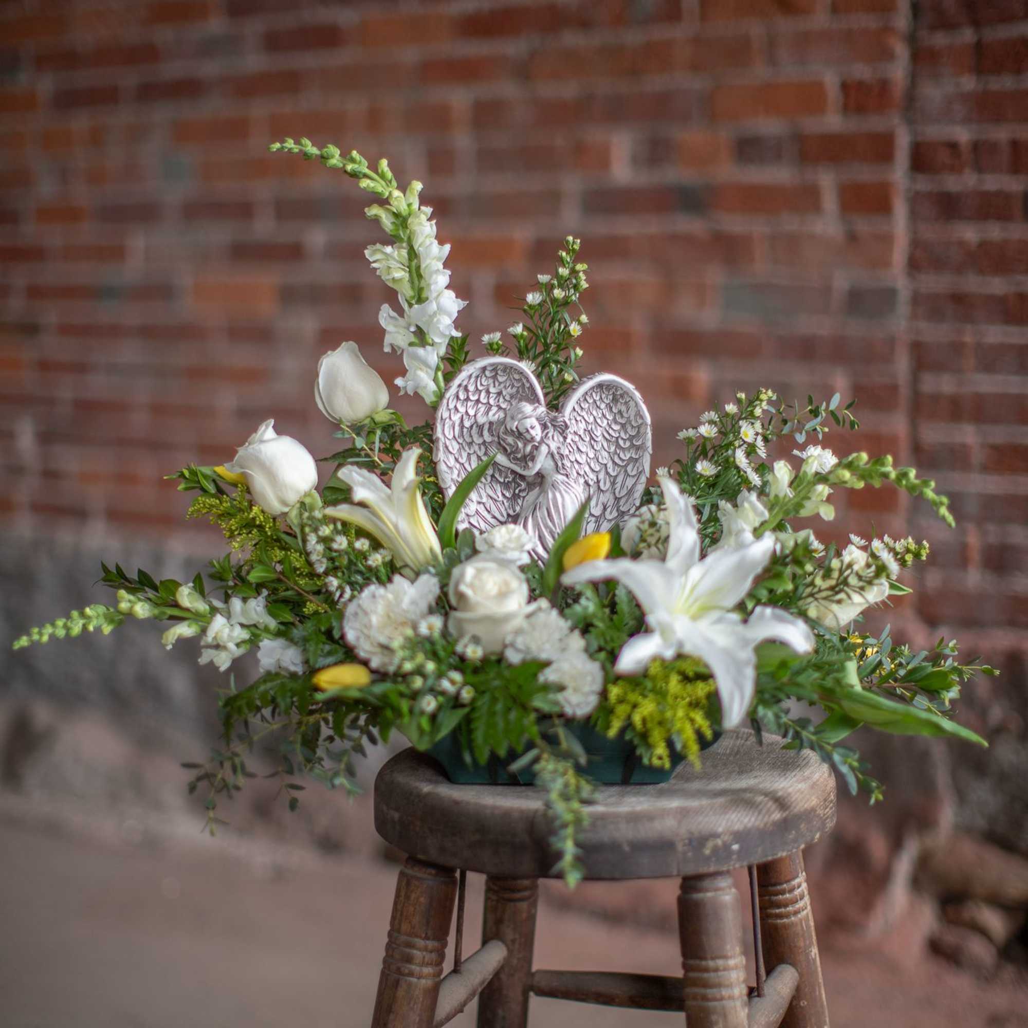 A lovely keepsake resin angel is nested into a garden floral design