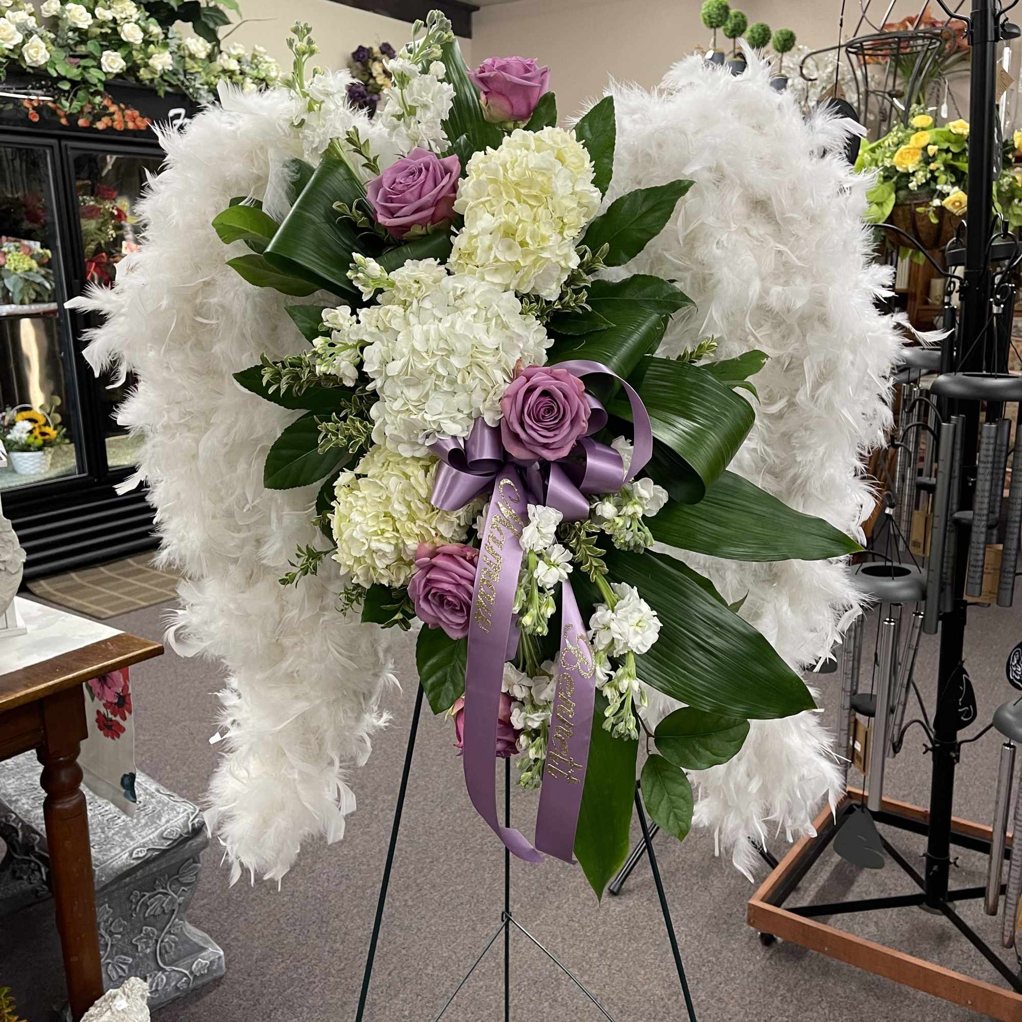 White and lavender floral standing spray with purple ribbon on an easel