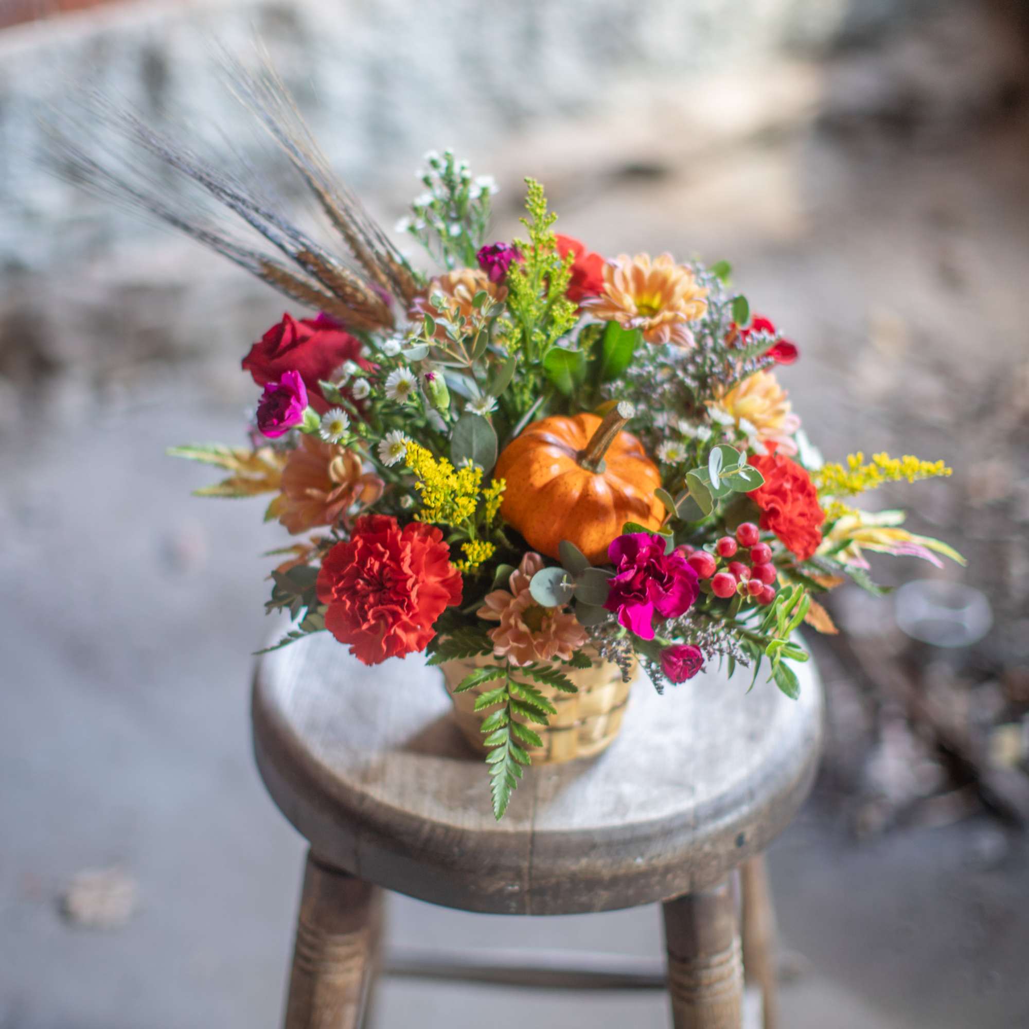 A mini pumpkin gourd pick is the focal point of the arrangement.