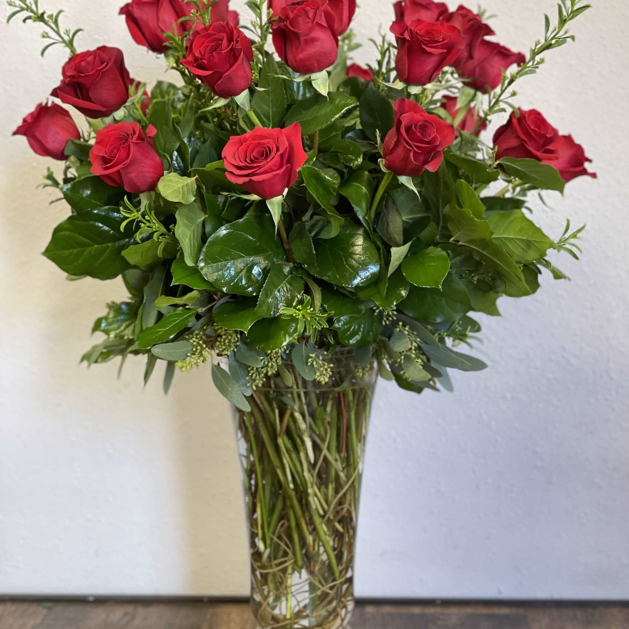 Tall arrangement of red roses in a clear glass vase