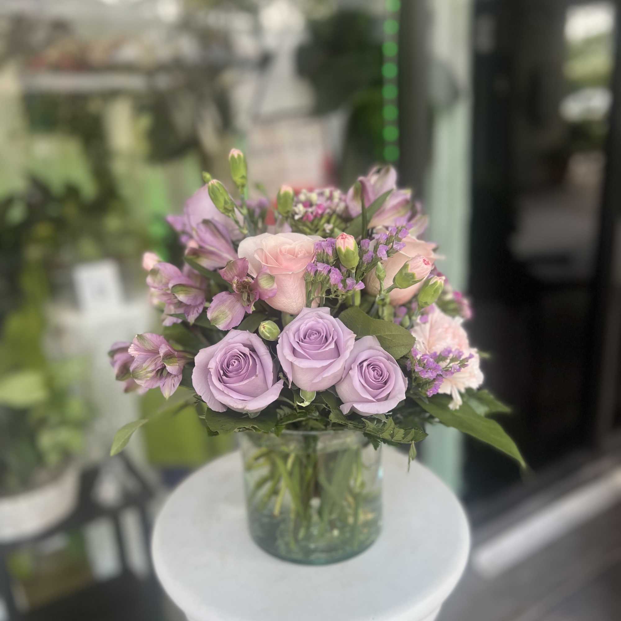 Lavender and pink roses arranged in a clear glass vase
