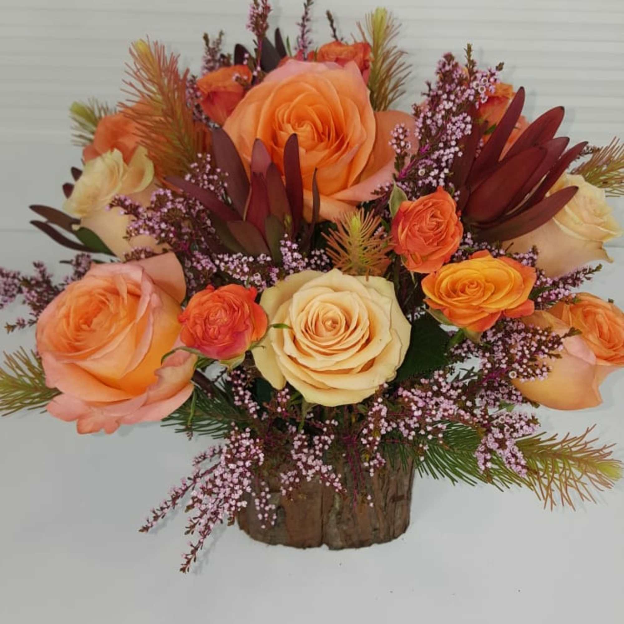 Warm Peach toned flowers in a square wooden vase