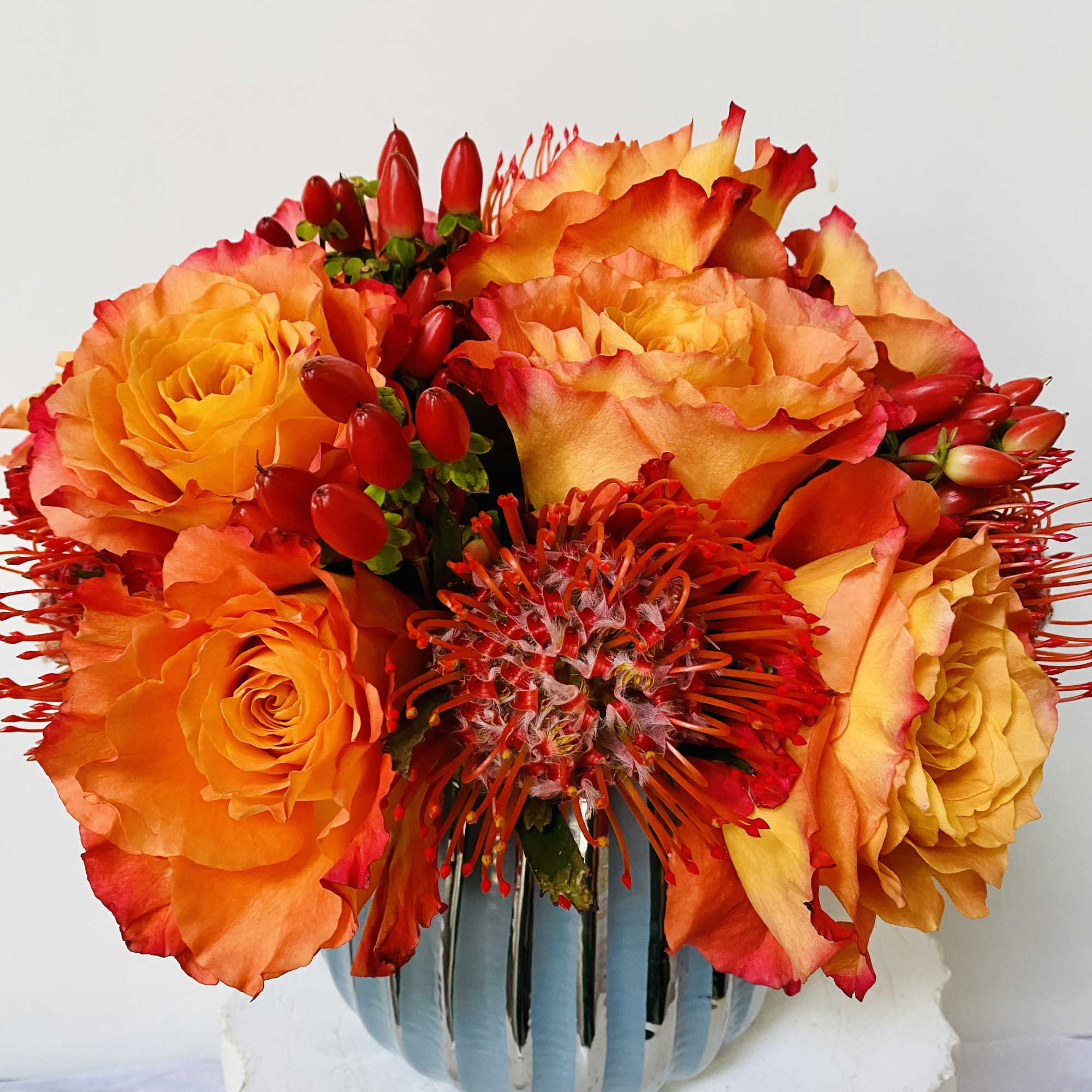 Orange and red roses arranged in a blue vase