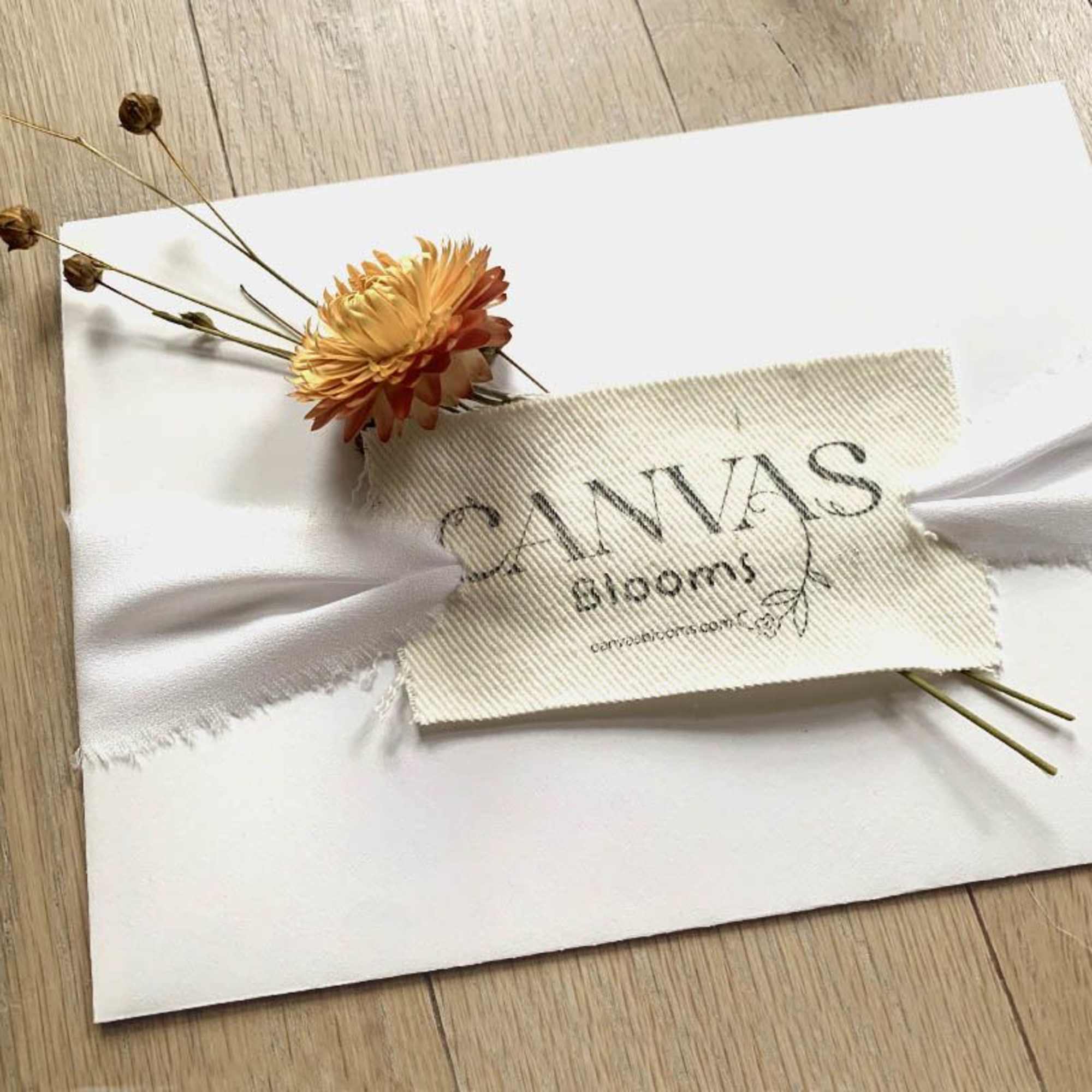 Single orange chrysanthemum with dried stems on a white card