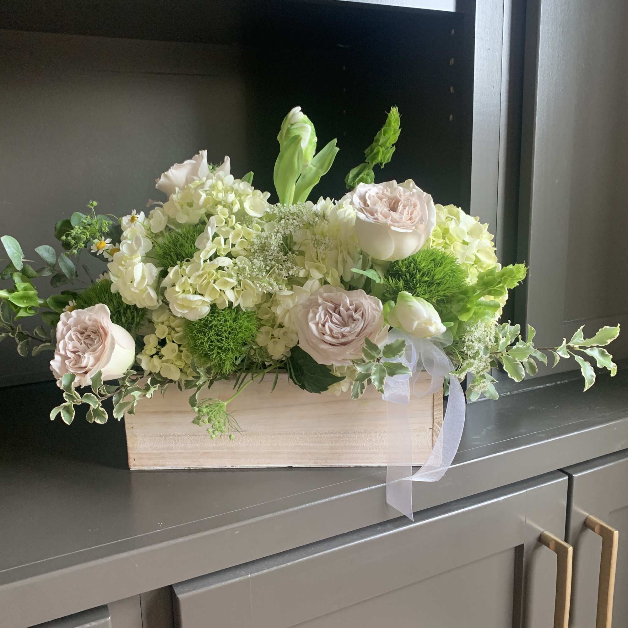 Low floral arrangement in a wooden box with pale pink roses and white blooms