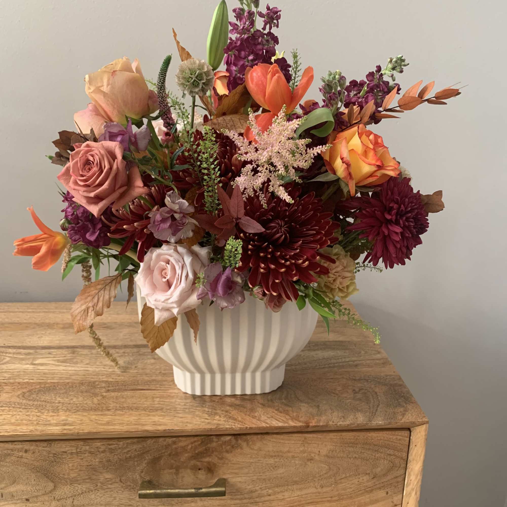 Mixed bouquet of roses, lilies, and chrysanthemums in a white vase