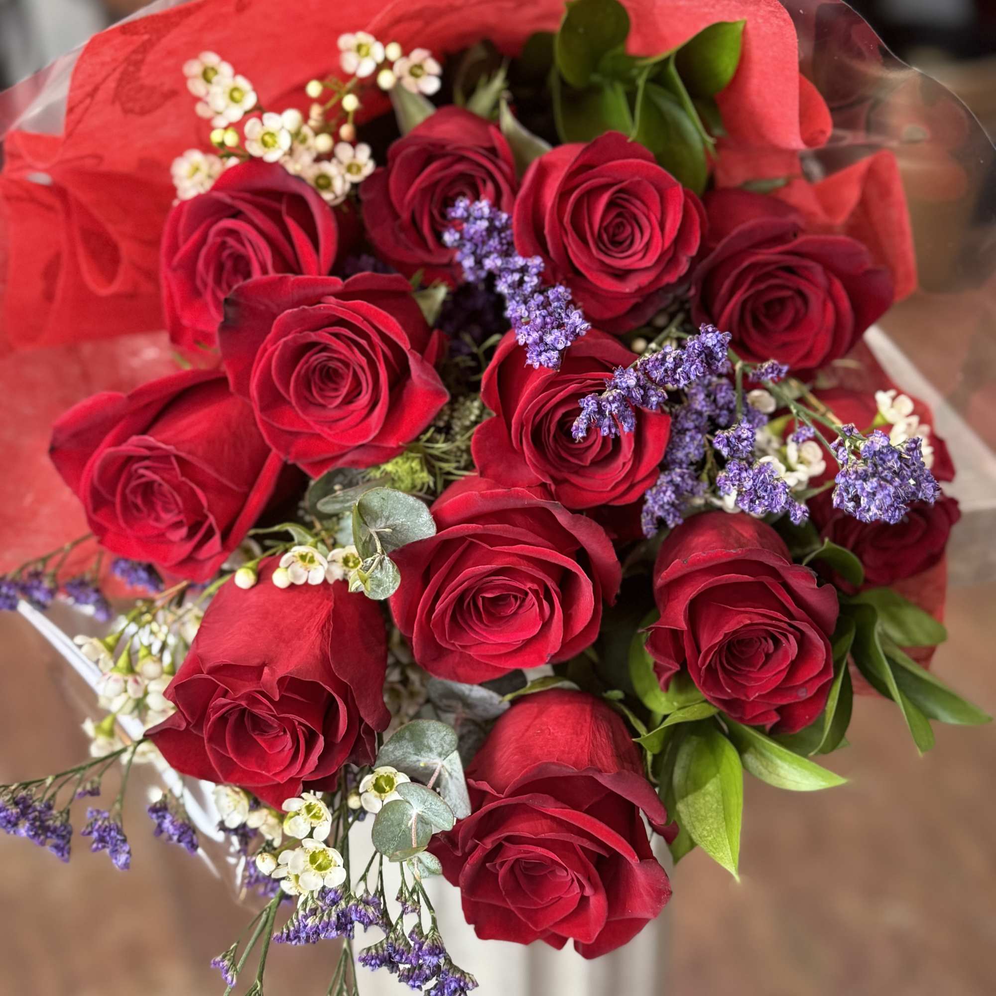 One dozen (or more) red roses arranged in a hand tied bouquet