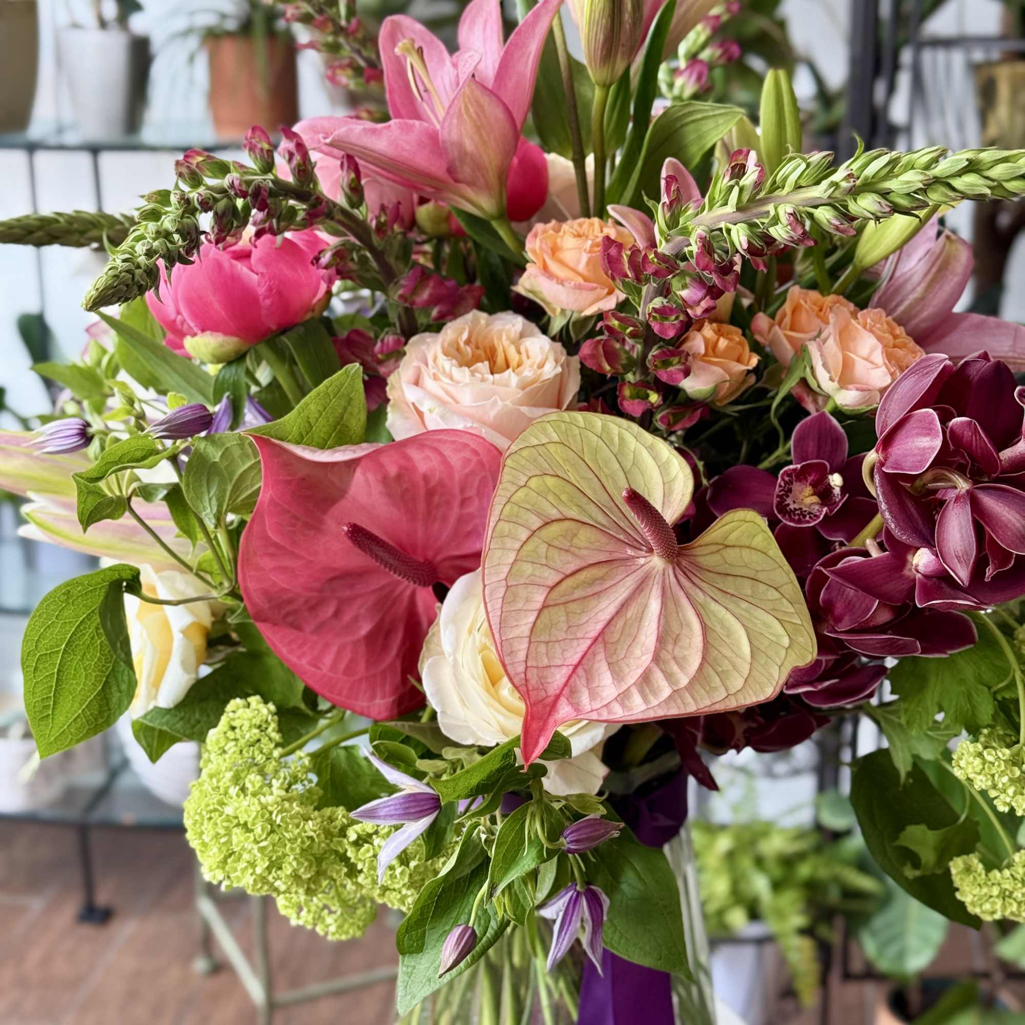 Mixed bouquet with pink lilies, roses, and orchids in a glass vase