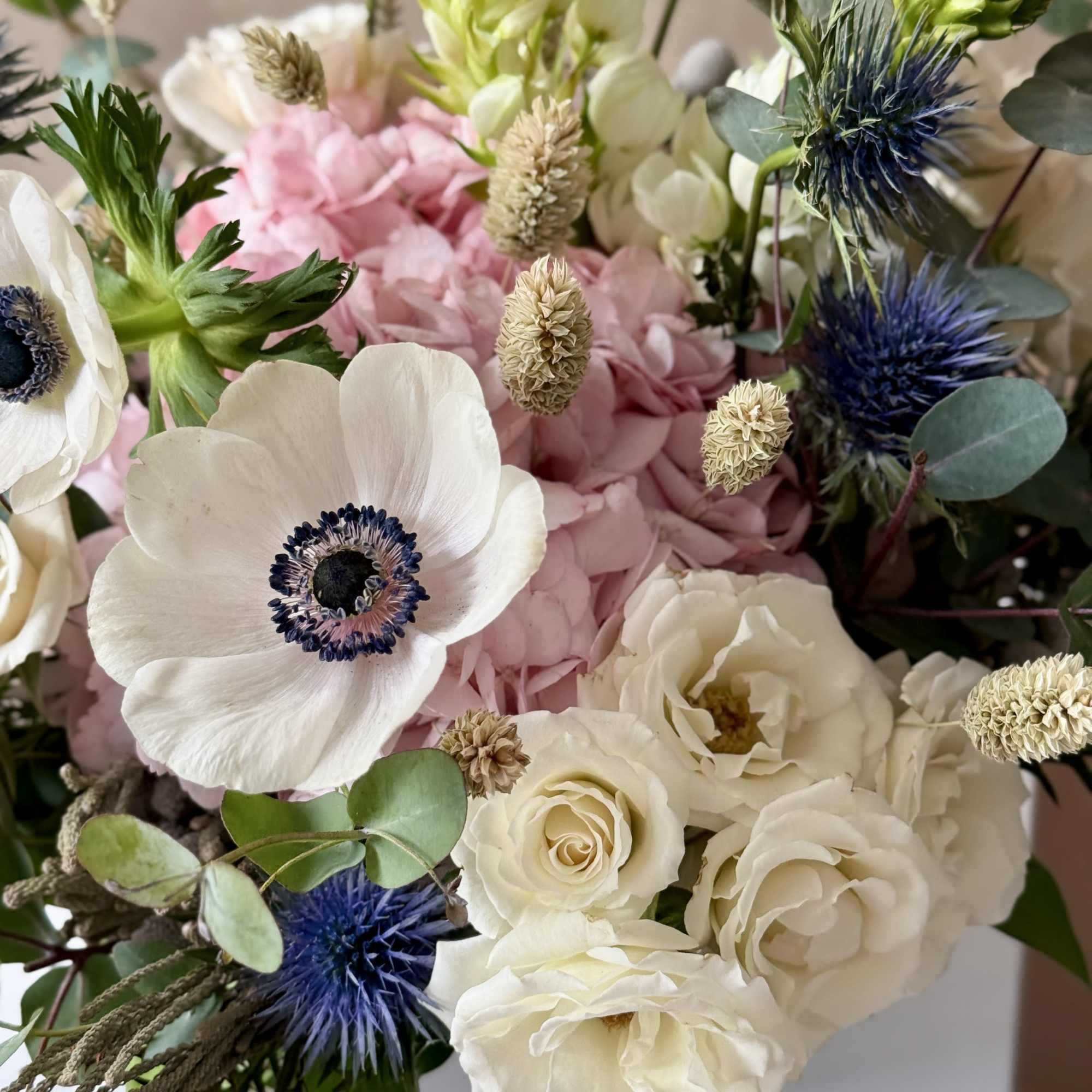 Bouquet of white and pink flowers with blue thistle accents
