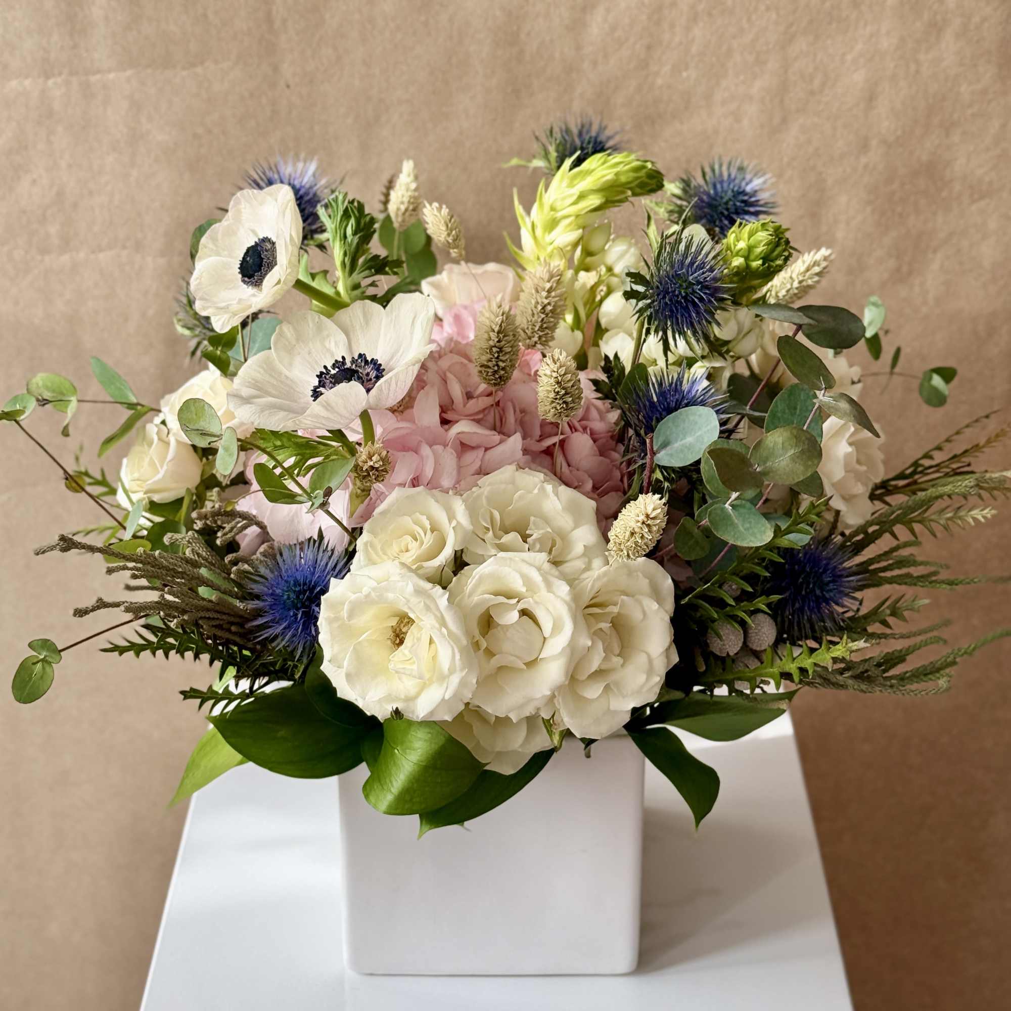 White and pink floral arrangement in a white square vase