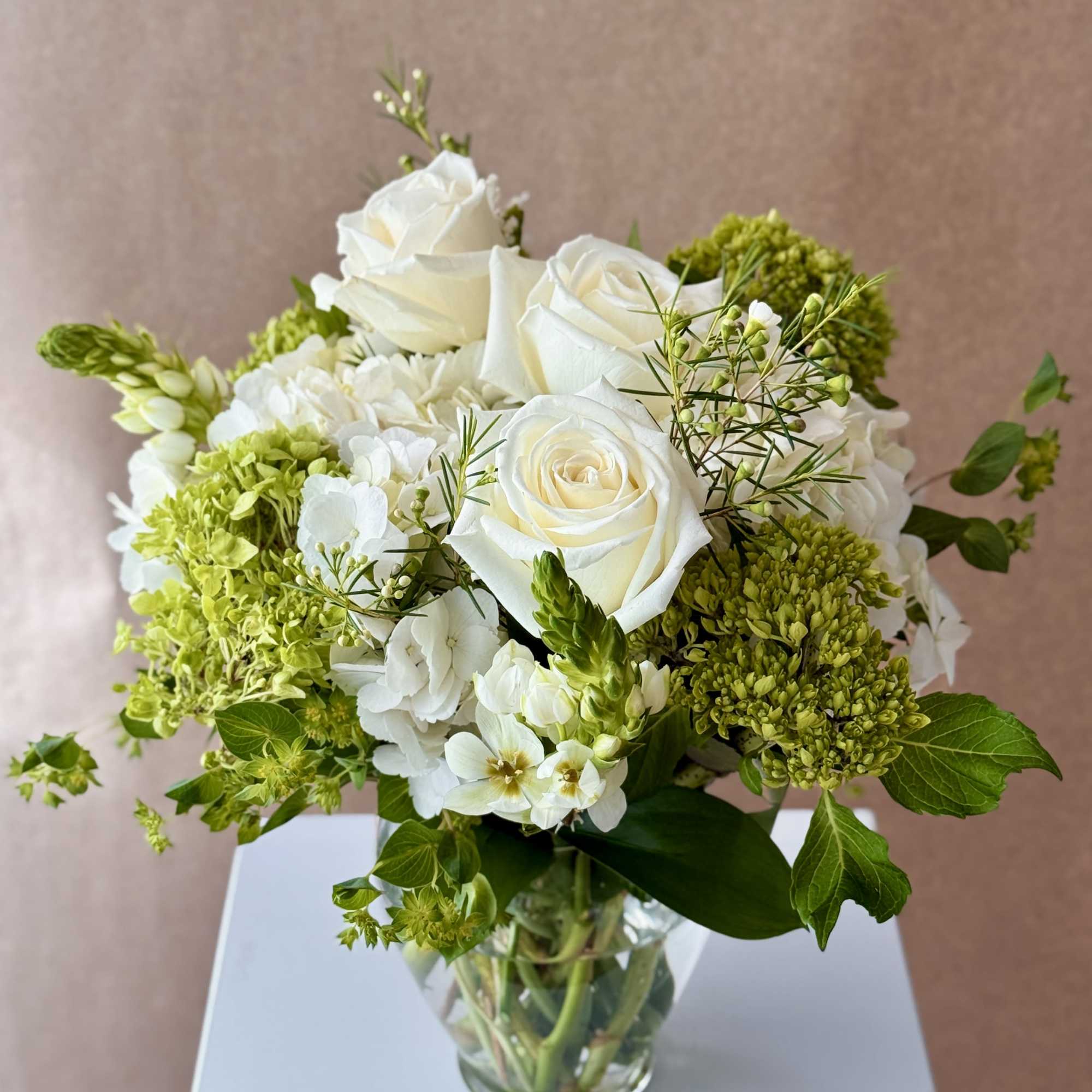 White roses and green hydrangeas in a clear glass vase