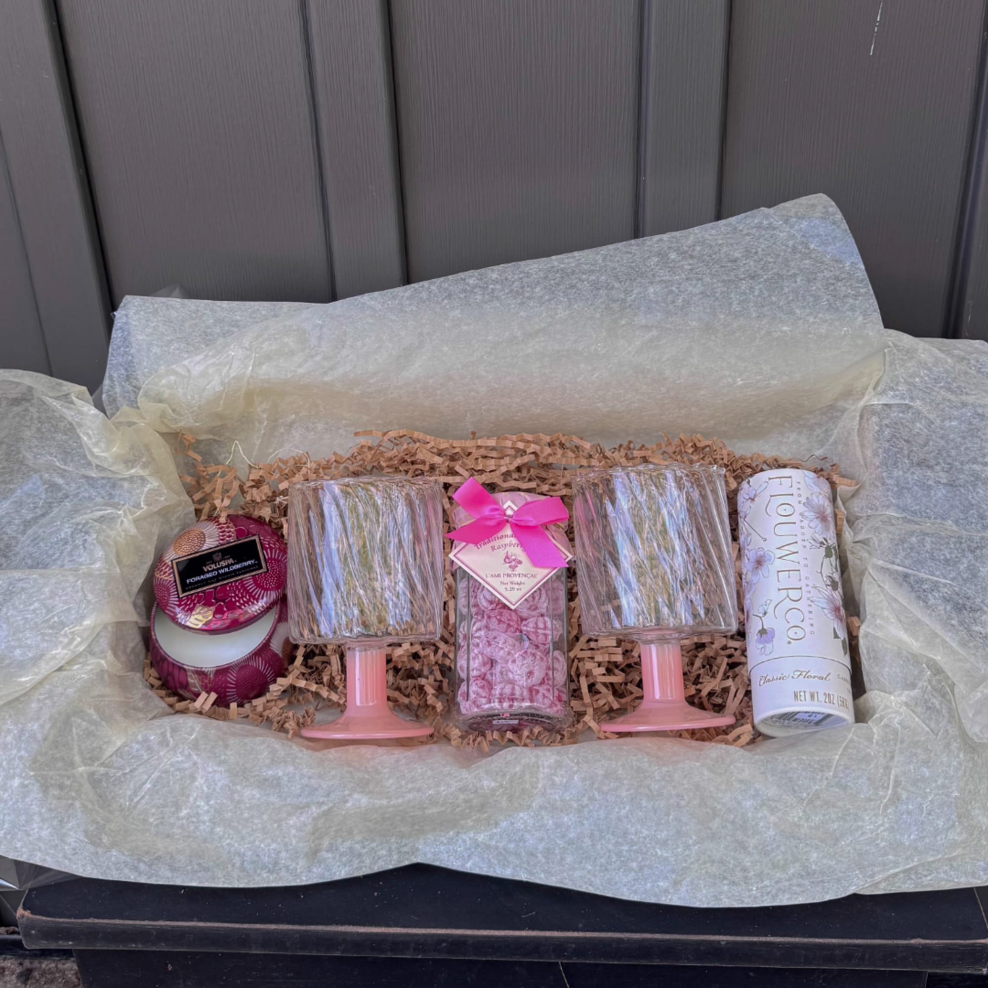 Gift box with candles and floral-scented items in tissue paper