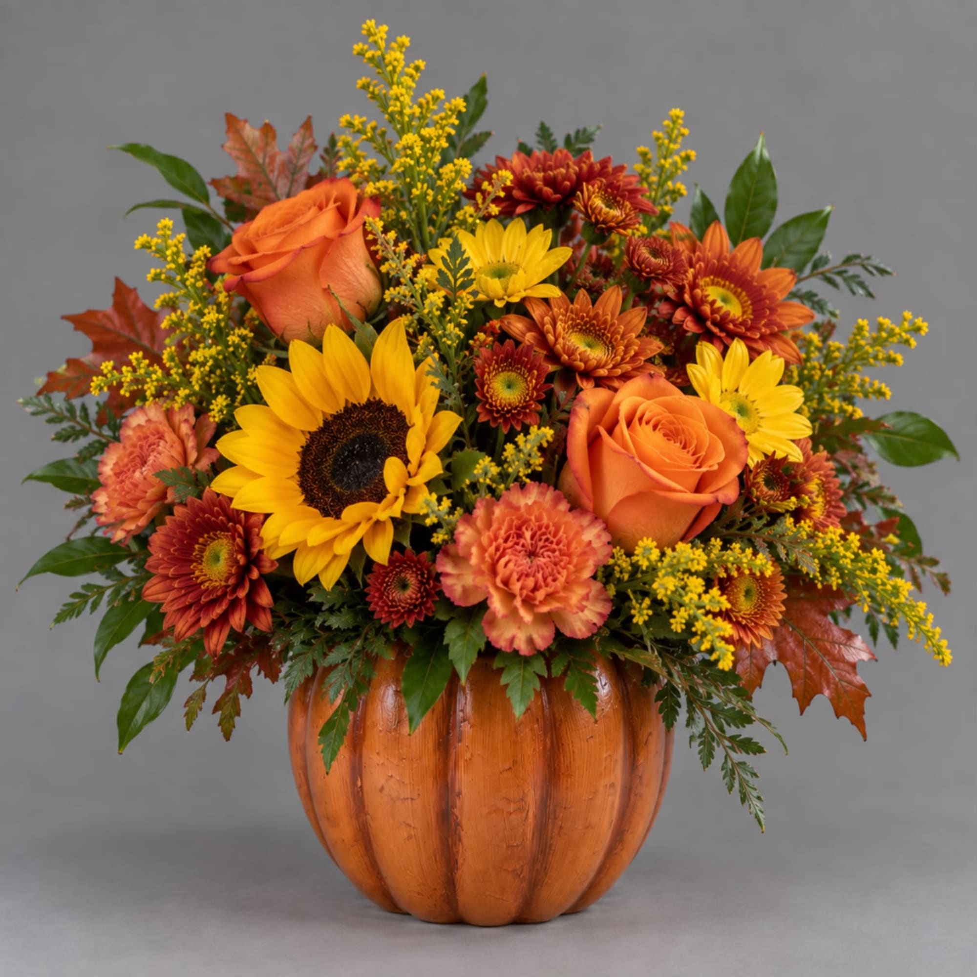 Autumn floral arrangement in a pumpkin-shaped container with sunflowers and orange roses
