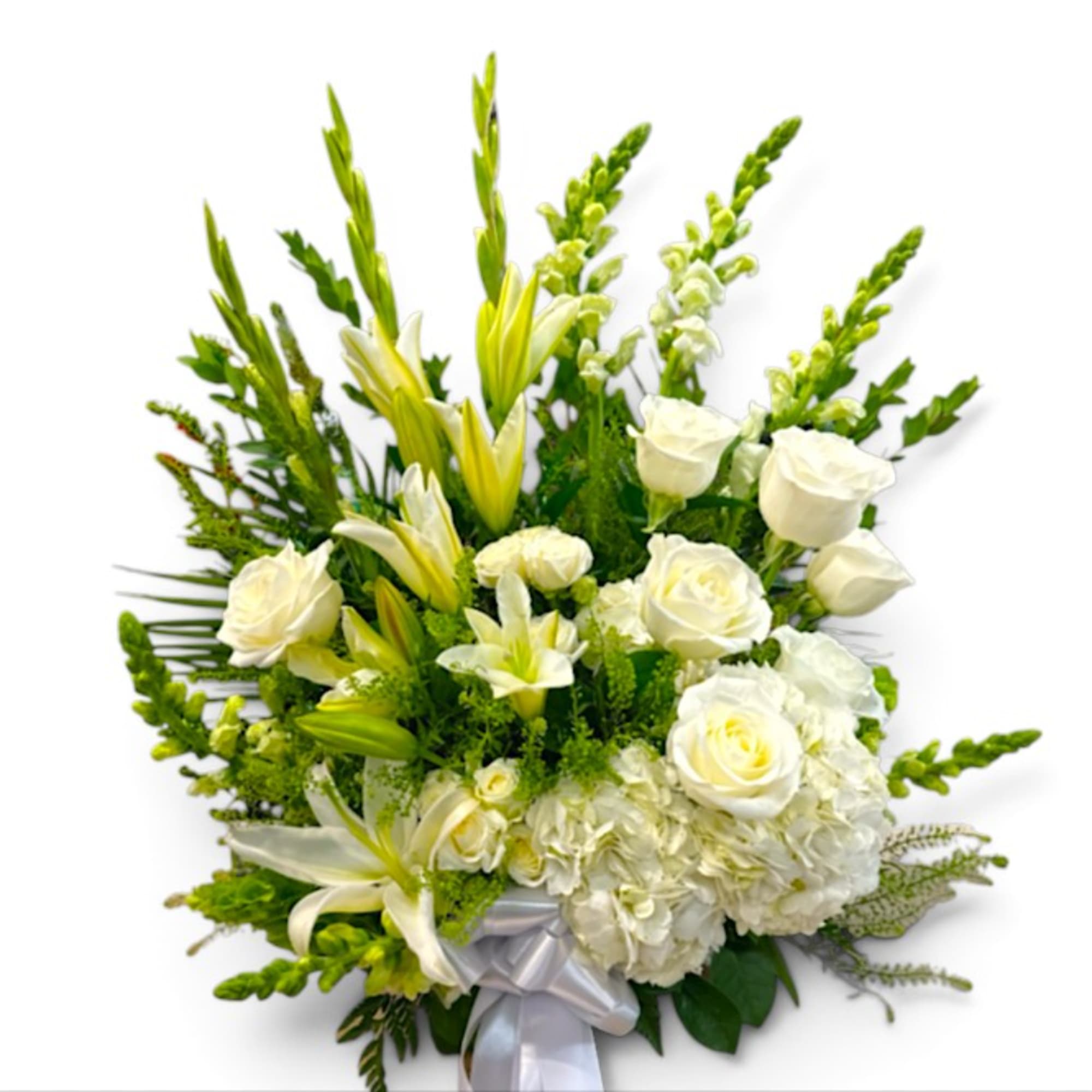 White roses and lilies arranged with green accents and a silver ribbon
