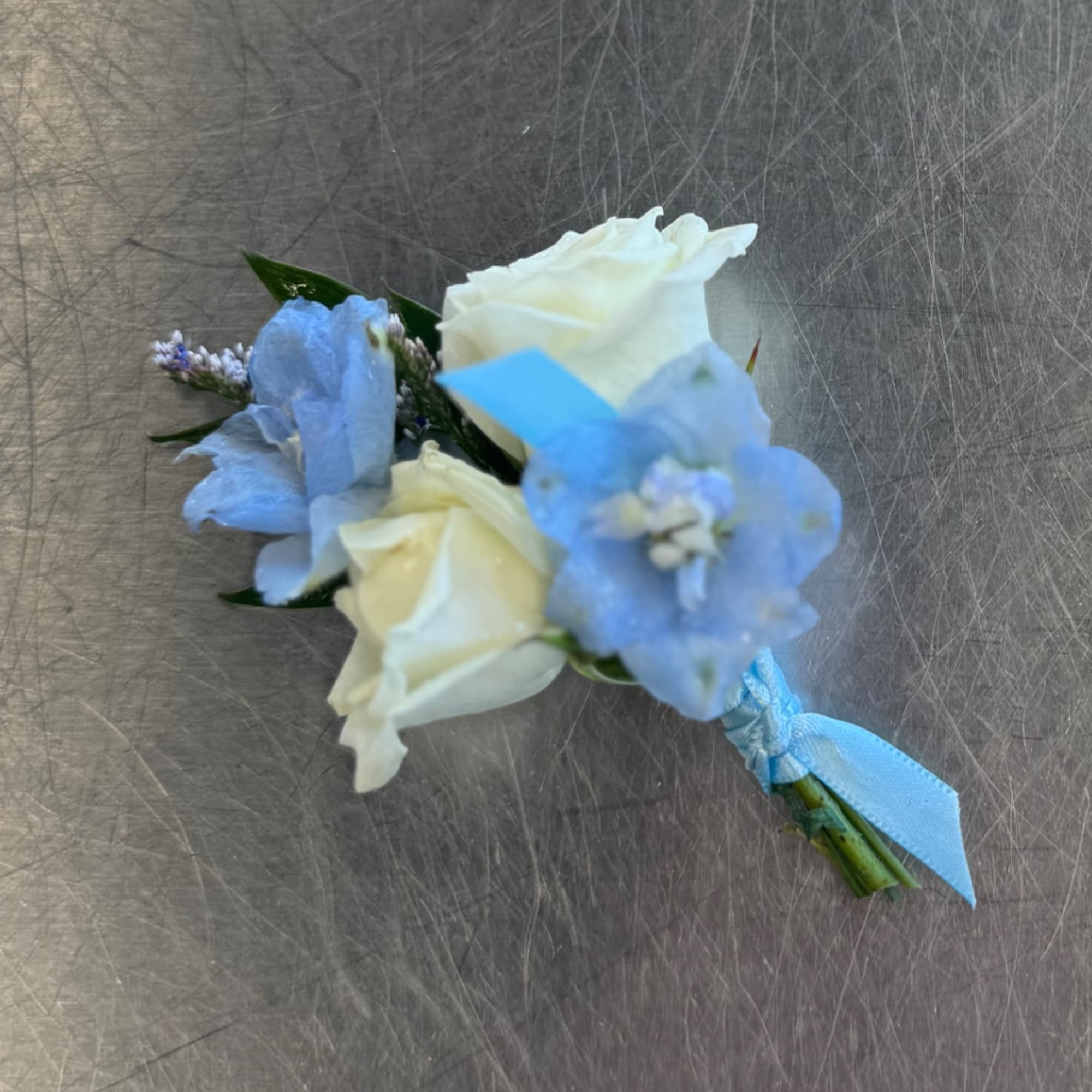 Small blue and white floral boutonniere with ribbon tie