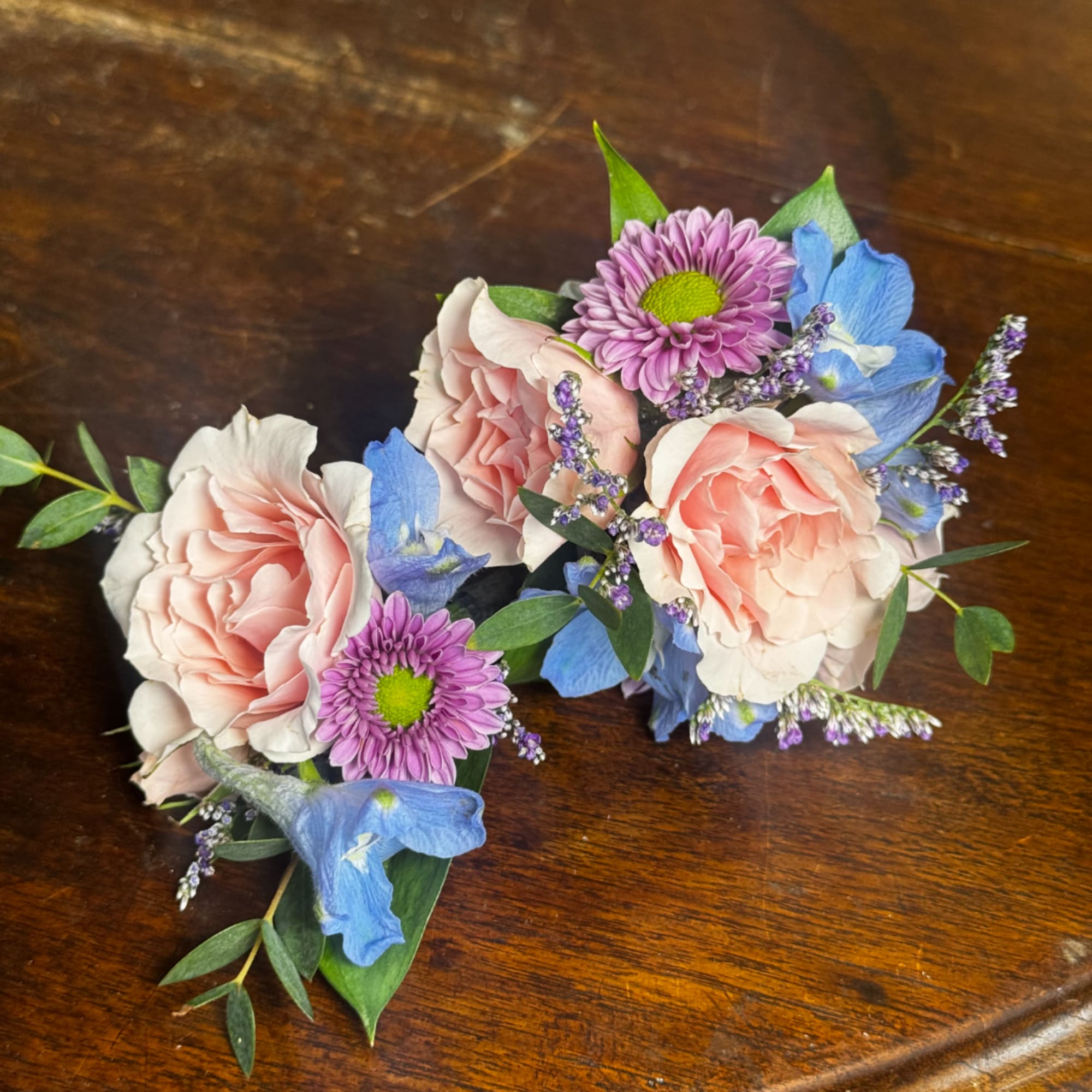 Two small floral bouquets with pink roses, purple daisies, and blue flowers