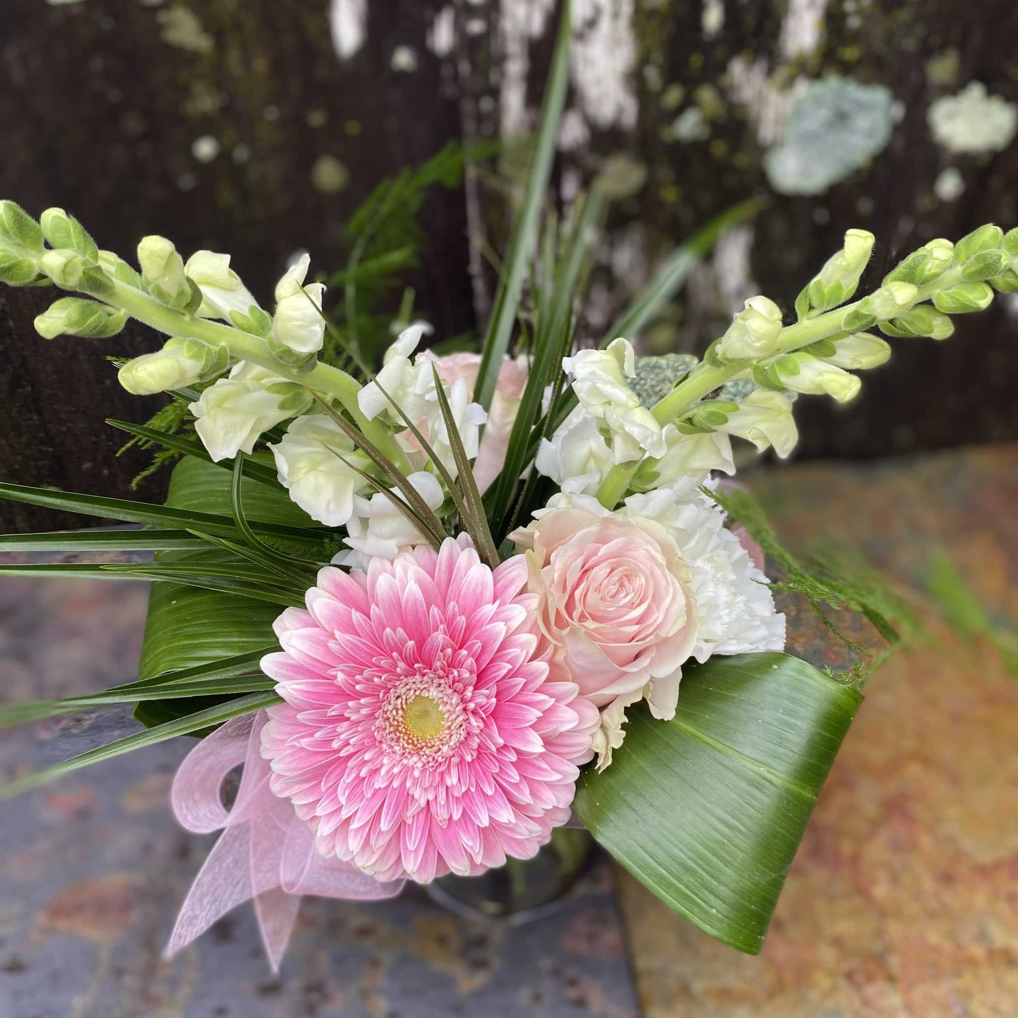 Pink gerbera daisy and pale roses in a bouquet with white blooms
