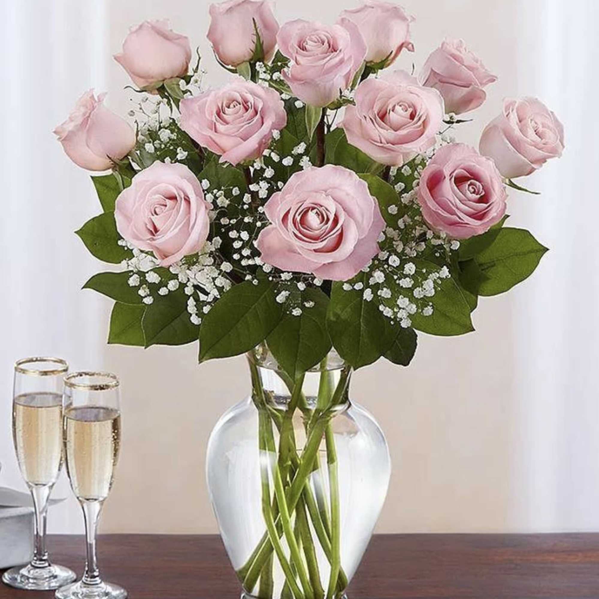 Pink roses arranged in a clear glass vase with small white filler flowers